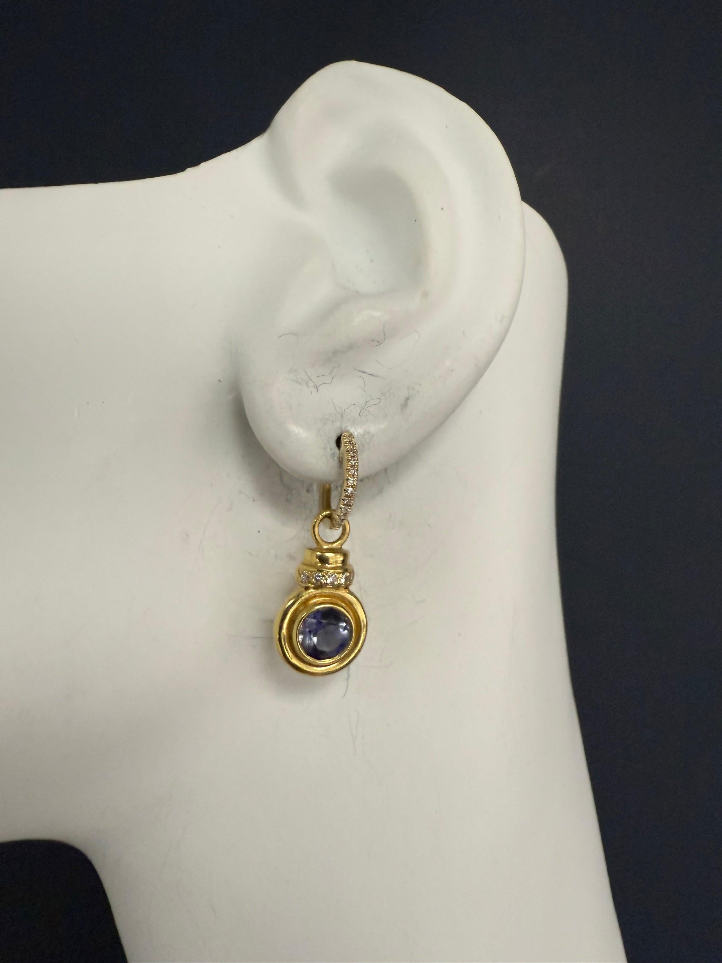 Orecchini retrò in oro giallo 18K con tsavoriti naturali tonde brillanti di colore bluastro-viola, del diametro di circa 5,7 mm, con 10 diamanti naturali incolori.
Gli orecchini misurano 10,5 mm di diametro e sono fissati a Brillianti da 14k con 24