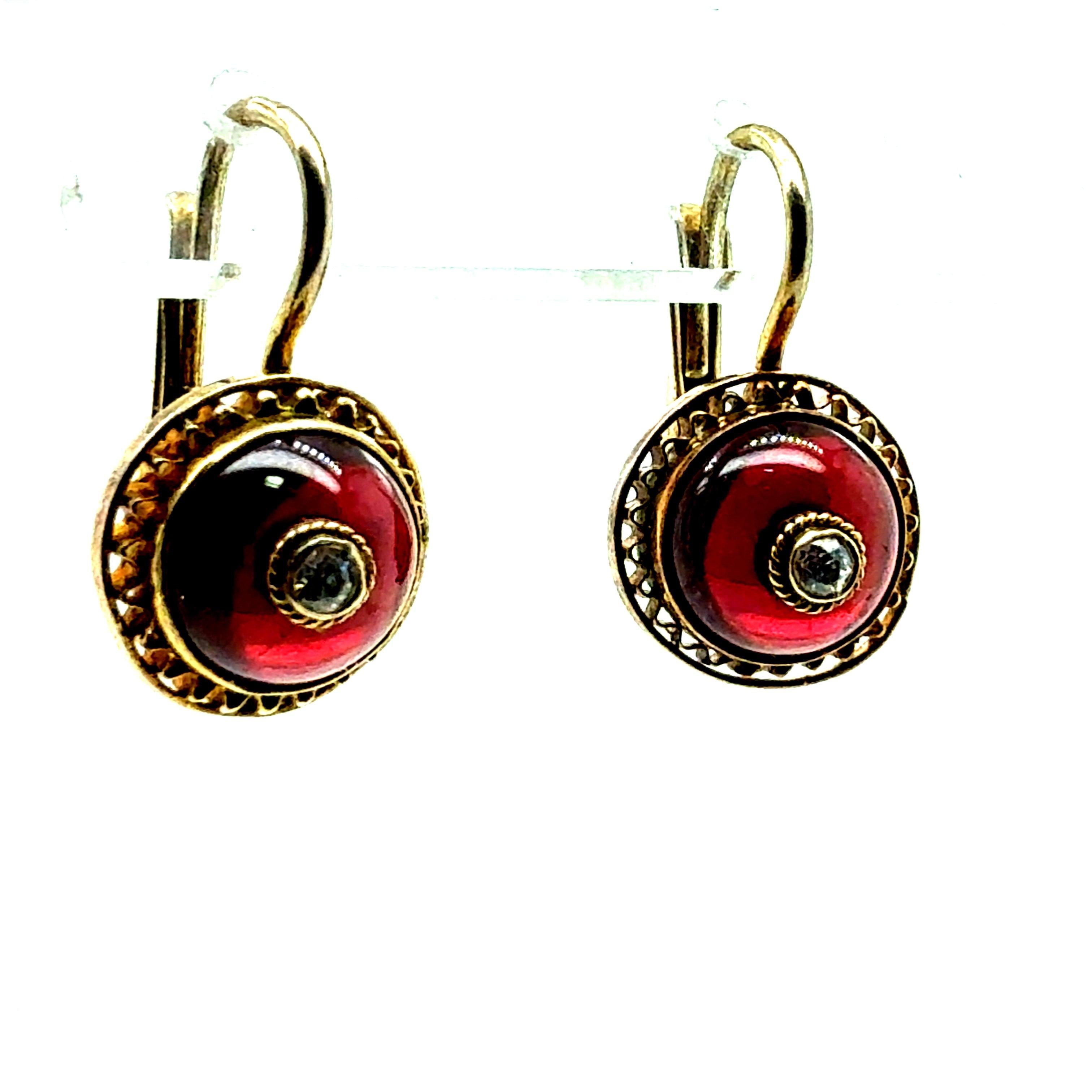 Retro yellow gold drop earrings featuring natural diamonds and rich red enamel accents. The design showcases exquisite handmade filigree work, adding depth and character. Each earring measures approximately 0.75 inches in length and 0.5 inches deep,