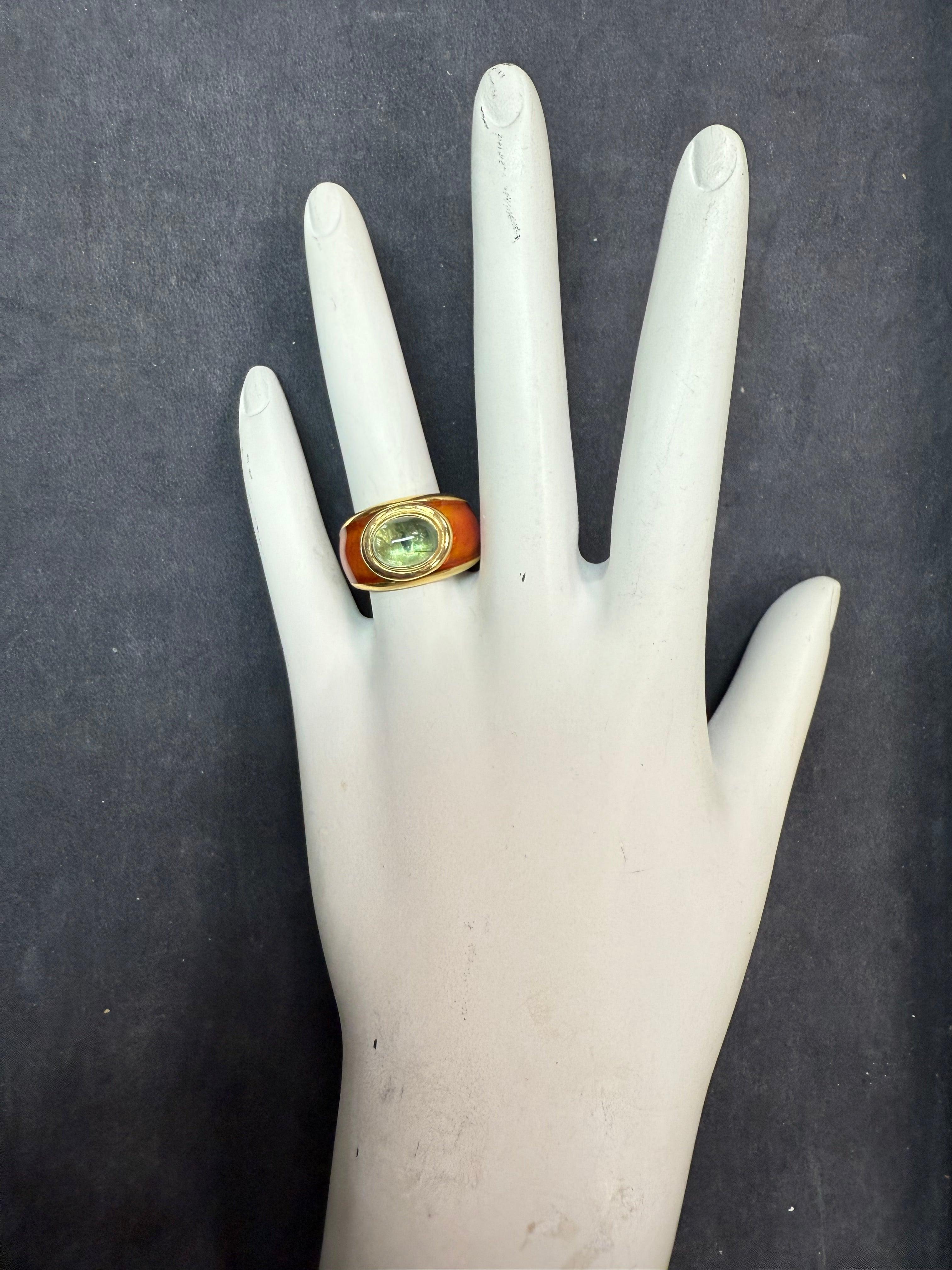 A retro oval cabochon tourmaline ring featuring rare enamel work. The cabochon measures approximately 9.7 x 7 mm and is set in a bold 18K yellow gold setting. The band measures 12 mm wide at the top and tapers to 5.8 mm at the bottom. Stamped 18K,