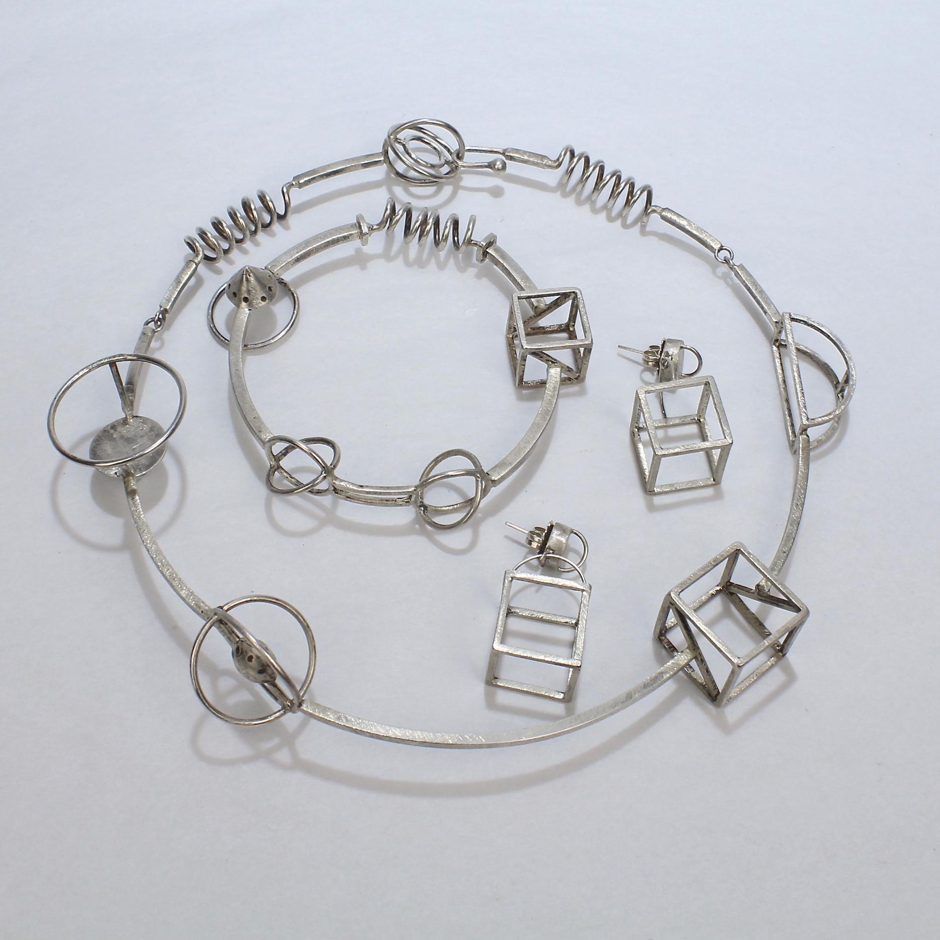 A Yumi Ueno necklace, earring, & bracelet parure.

In sterling silver.

With 3-dimensional wire formed geometric shapes that are attached to stiff wire structures. 

The playfulness of the pieces gives the feeling of movement in space.

Simply a