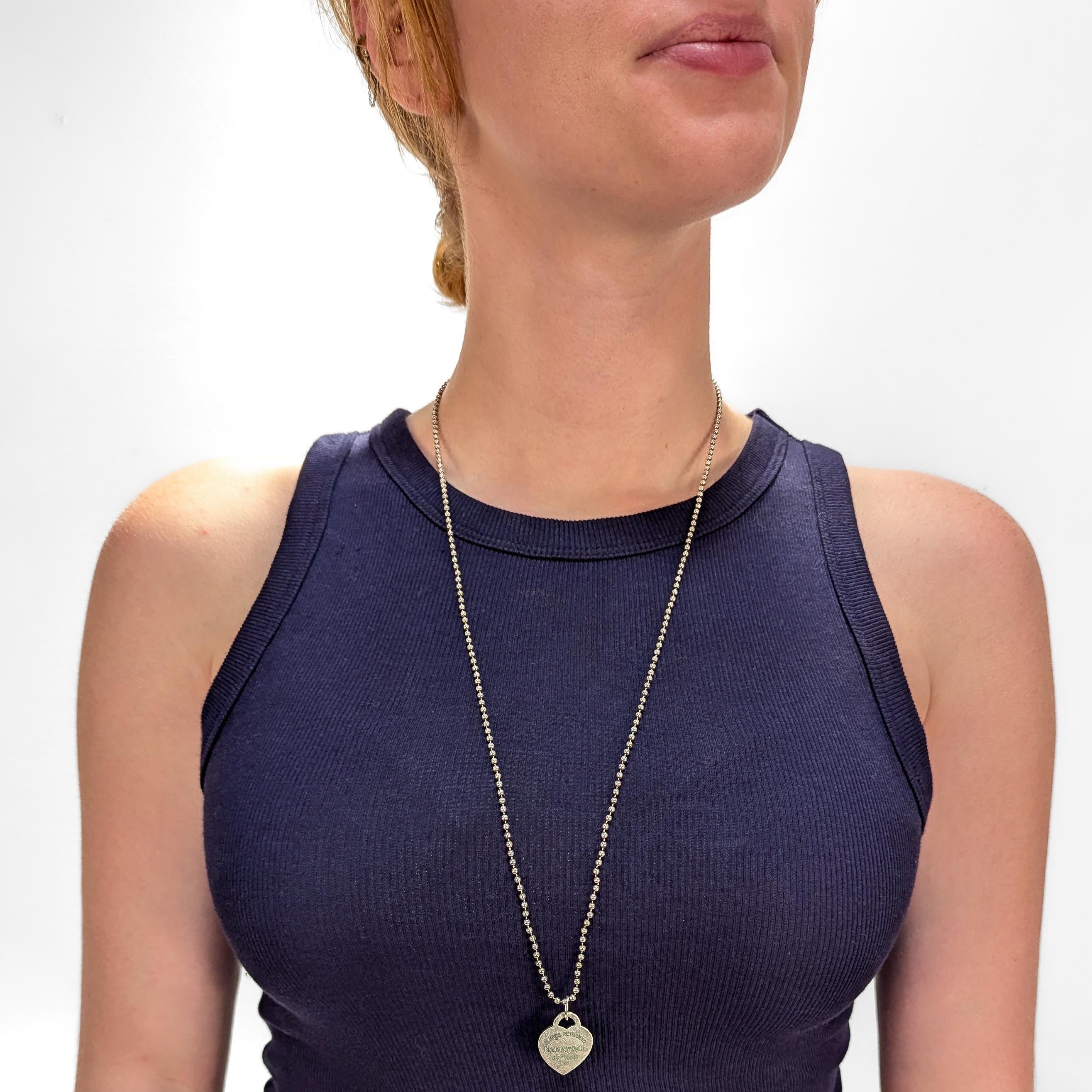 Un collar de plata fina con etiqueta de corazón.

De Tiffany & Co.

En plata de ley.

Con un colgante en forma de corazón grabado y con incrustaciones de esmalte azul Tiffany que reza: 