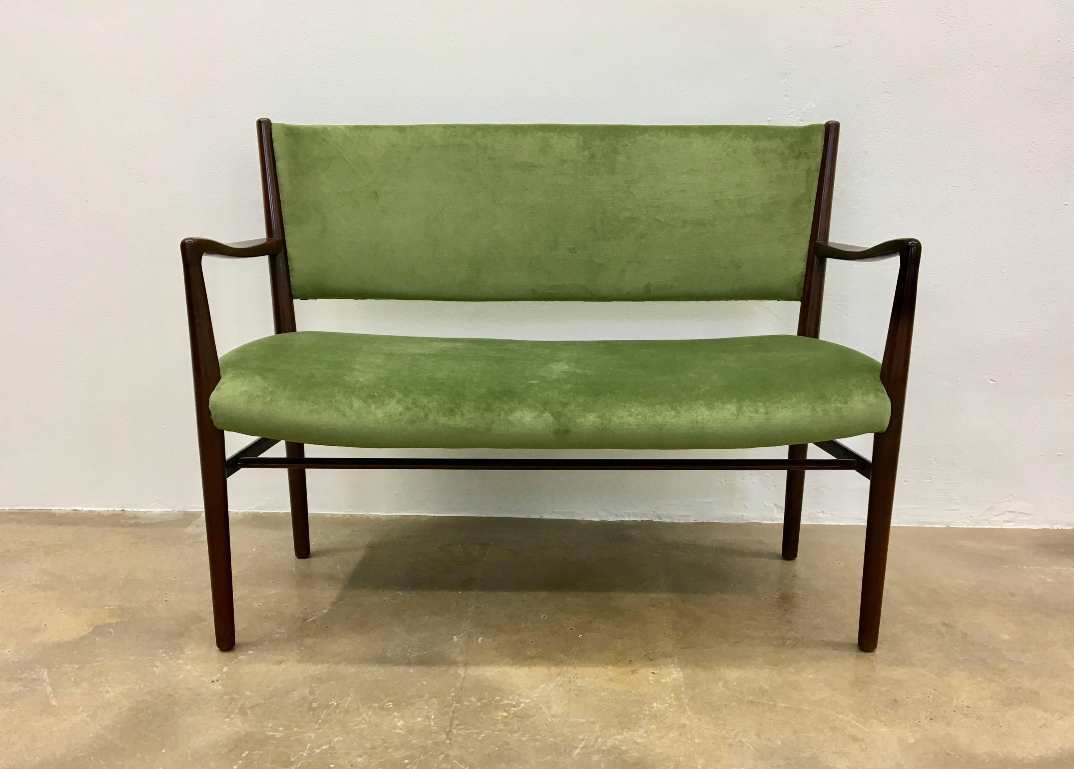 This two-seat bench was produced in Denmark, circa 1950s. It is made from mahogany and is upholstered with green velvet.