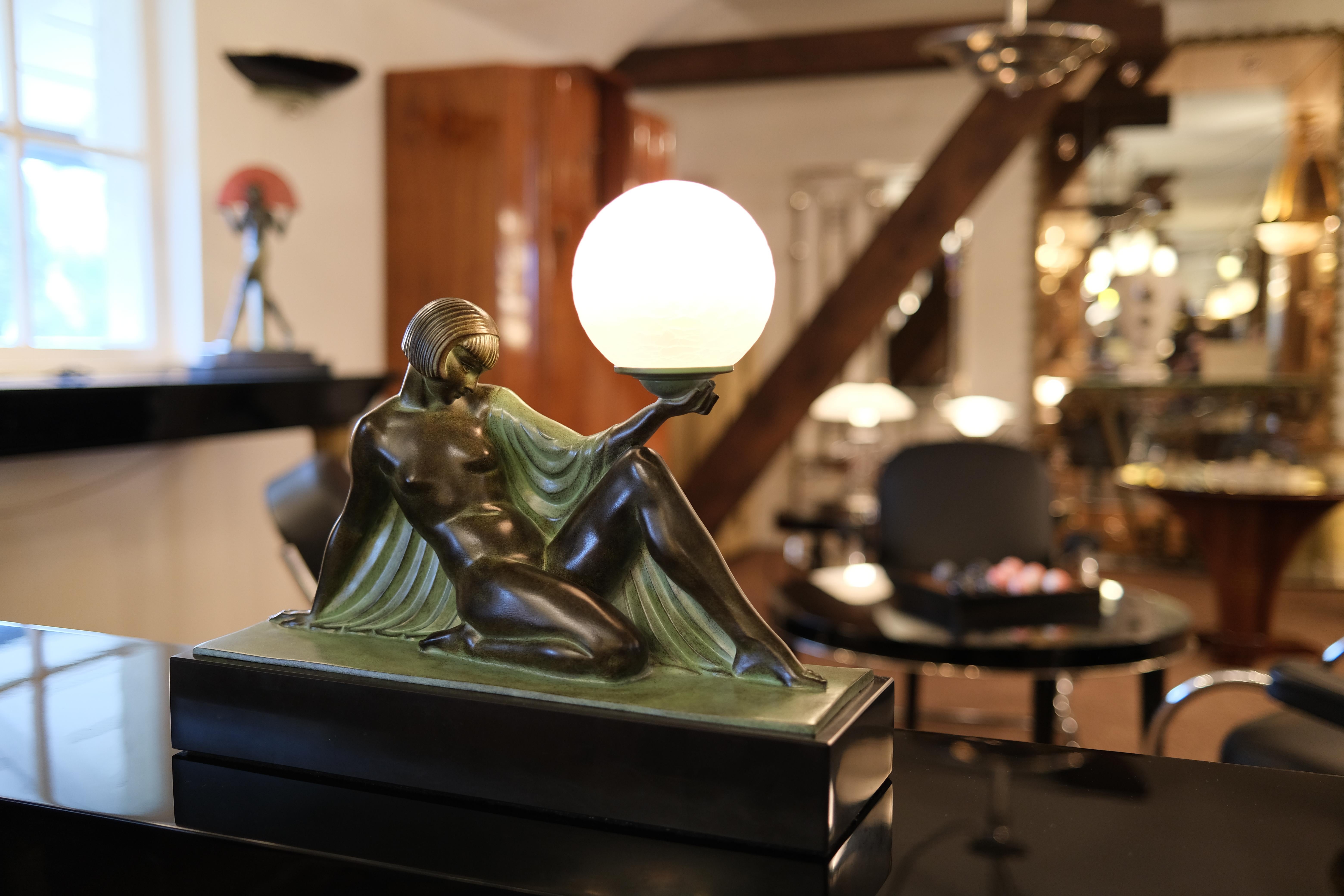 Table lamp “Reverie” 
Reverie is French for musing. 
Sculpture / Figure. 
Nude lady holding a lighted glass ball. 
Designed in France during the roaring 1920s by “Raymonde Guerbe” (1894-1995) 
She was married with the famous sculptor 