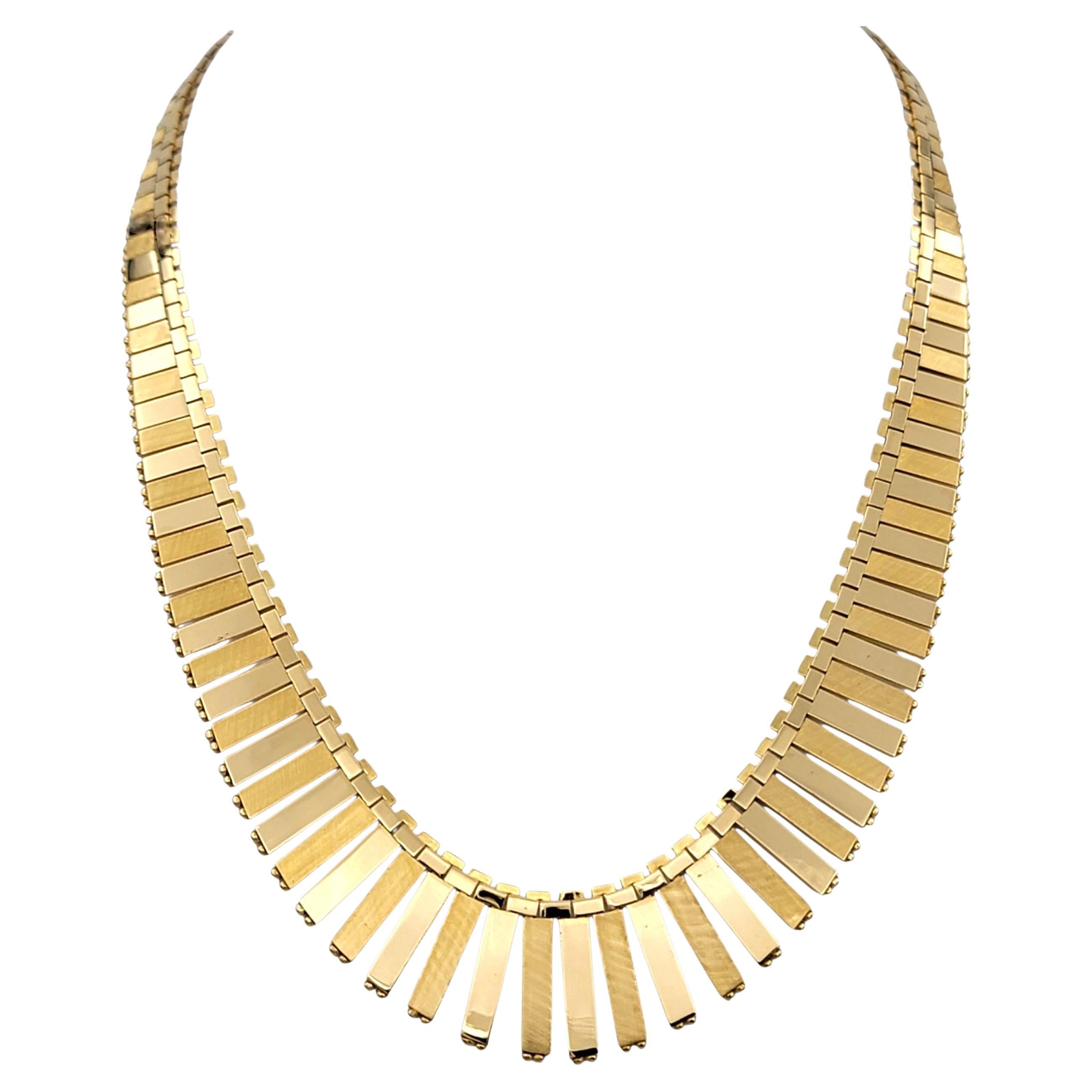 This striking necklace is crafted in rich 18 karat yellow gold and designed in a reversible graduated bib style. Each section is meticulously arranged to create a bold yet elegant statement, with a polished finish that highlights the flowing,
