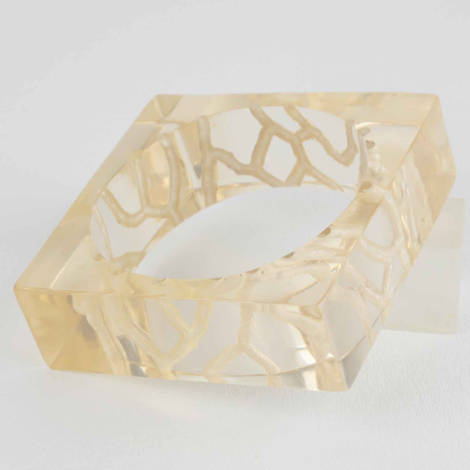 This stunning acrylic lucite bangle bracelet boasts an oversized square shape with striped, reverse-carved inclusions. The bangle is a lovely transparent light yellow champagne color, and there is no visible designer's mark.
Measurements: inside