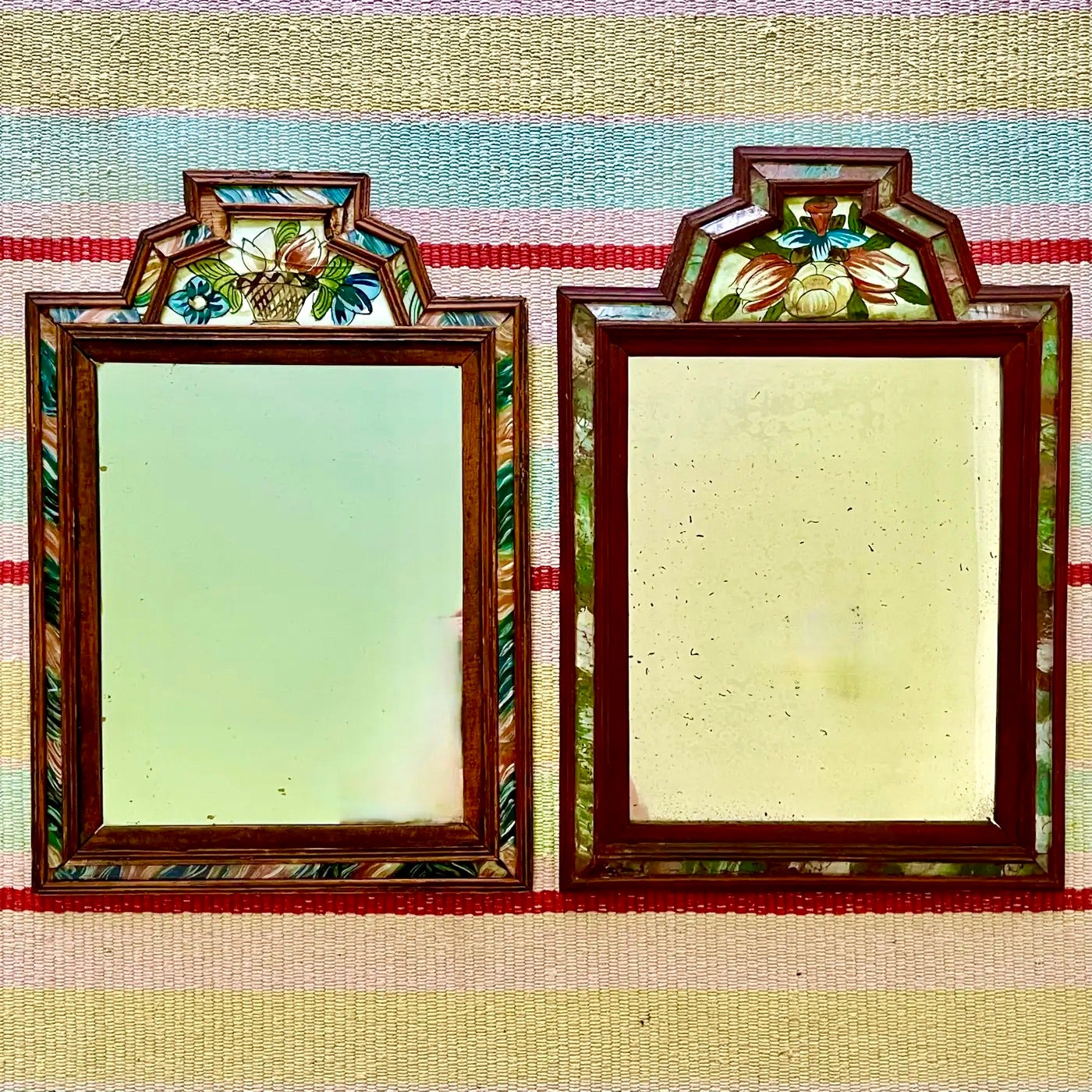 A pair of European wood and reverse painted glass Courting Mirrors with floral motif crests and marbleized panels, circa 1780-1820.

Courting mirrors were given as a courting gift and often hung in hallways for last minute grooming. They are made of