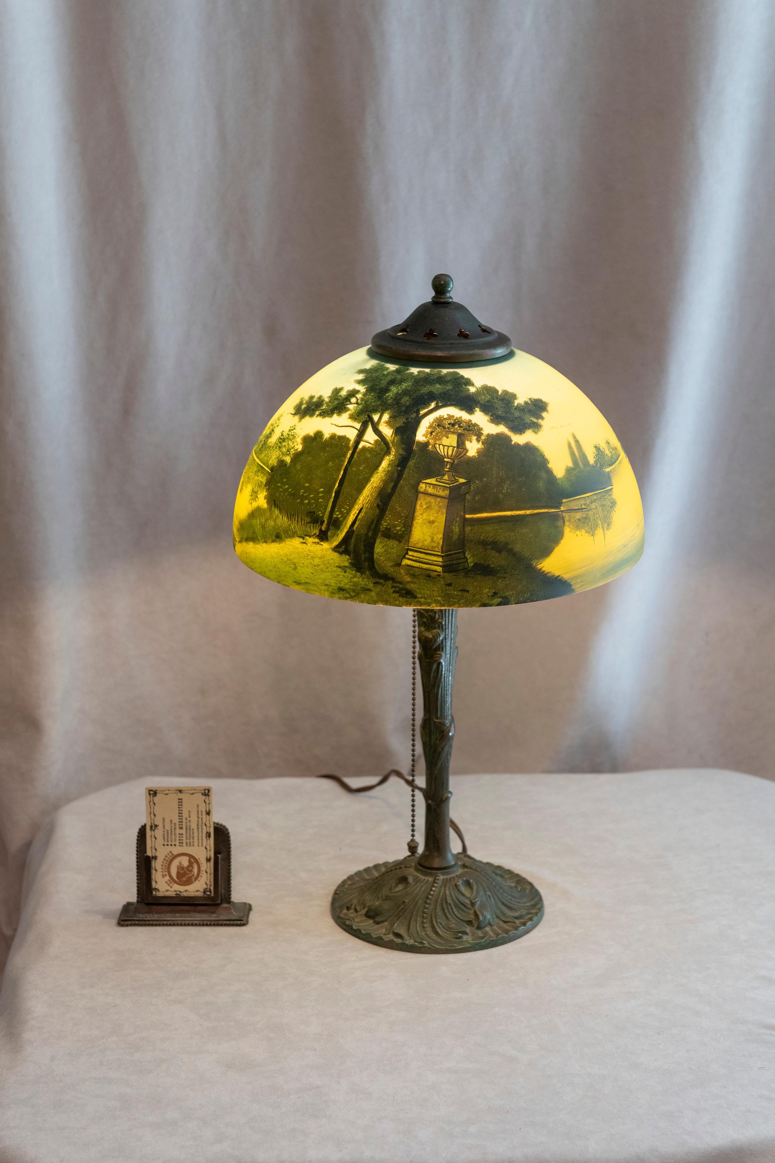 This reverse painted table lamp we know to be produced by Phoenix. It is on the original base and also has the original heat cap and finial. This lamp is so original, that no one ever thought to remove the paper label on the inside of the shade that