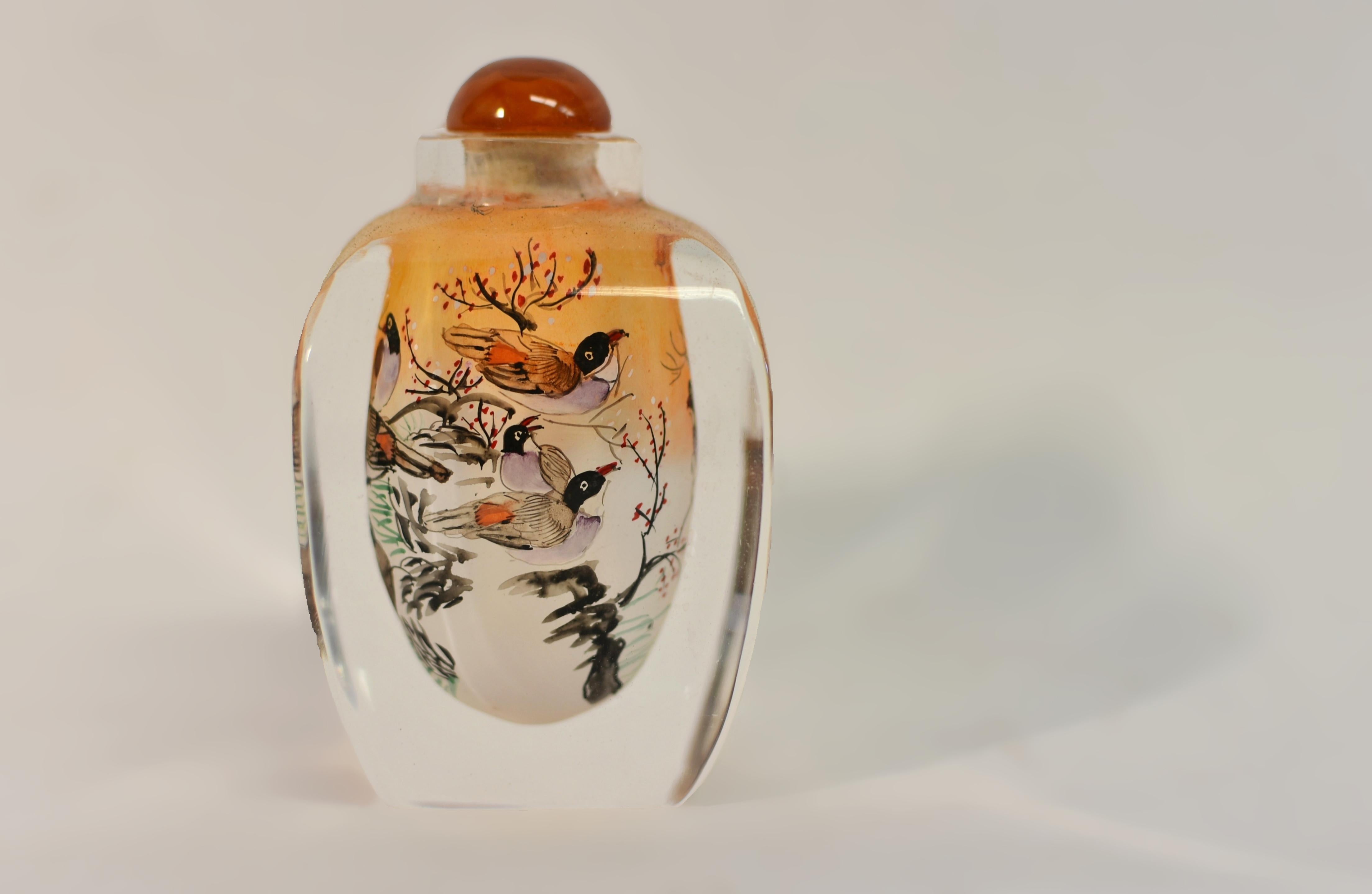 Die chinesische Eglomise-Schnupftabakflasche ist ein fesselndes Meisterwerk, das die feine Kunst der Hinterglasmalerei von innen zeigt. Die Szene zeigte eine Gruppe von Vögeln, die auf einem Pflaumenblütenbaum in einer ruhigen Schneelandschaft