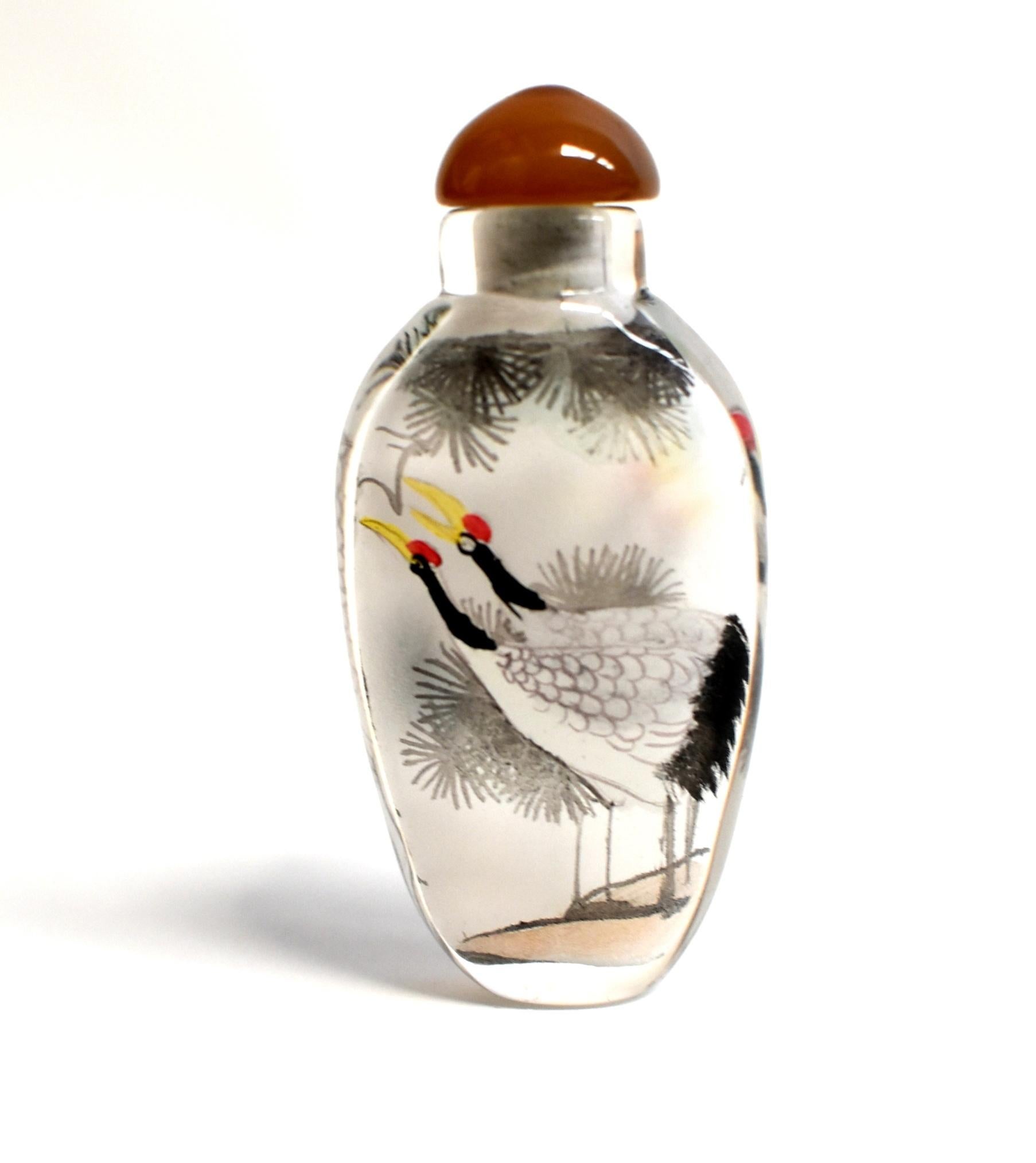 Our snuff bottles are topped with gemstone grade agate lids and 100% hand painted from within. The Chinese art of églomisé uses a very thin bamboo brush with a few strands of hair to apply watercolor on the inside walls of the blank glass bottle
