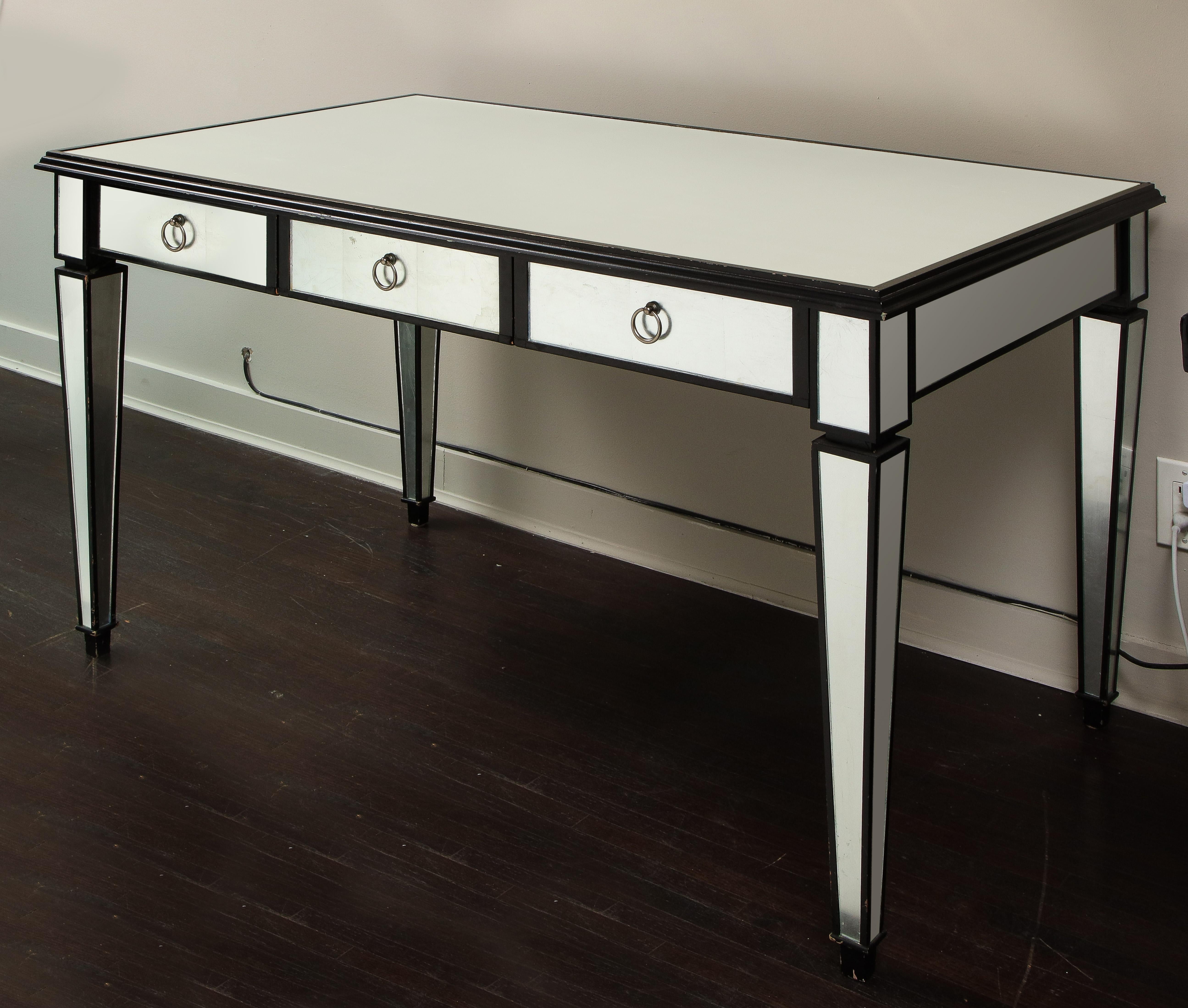 Floor model of reverse silver leaf glass desk with black lacquer trim. A perfect modern transitional style desk in a monochromatic tone. The desk shows some wear on trims and minor silvering. Touch-ups on the trims will be done upon purchase.