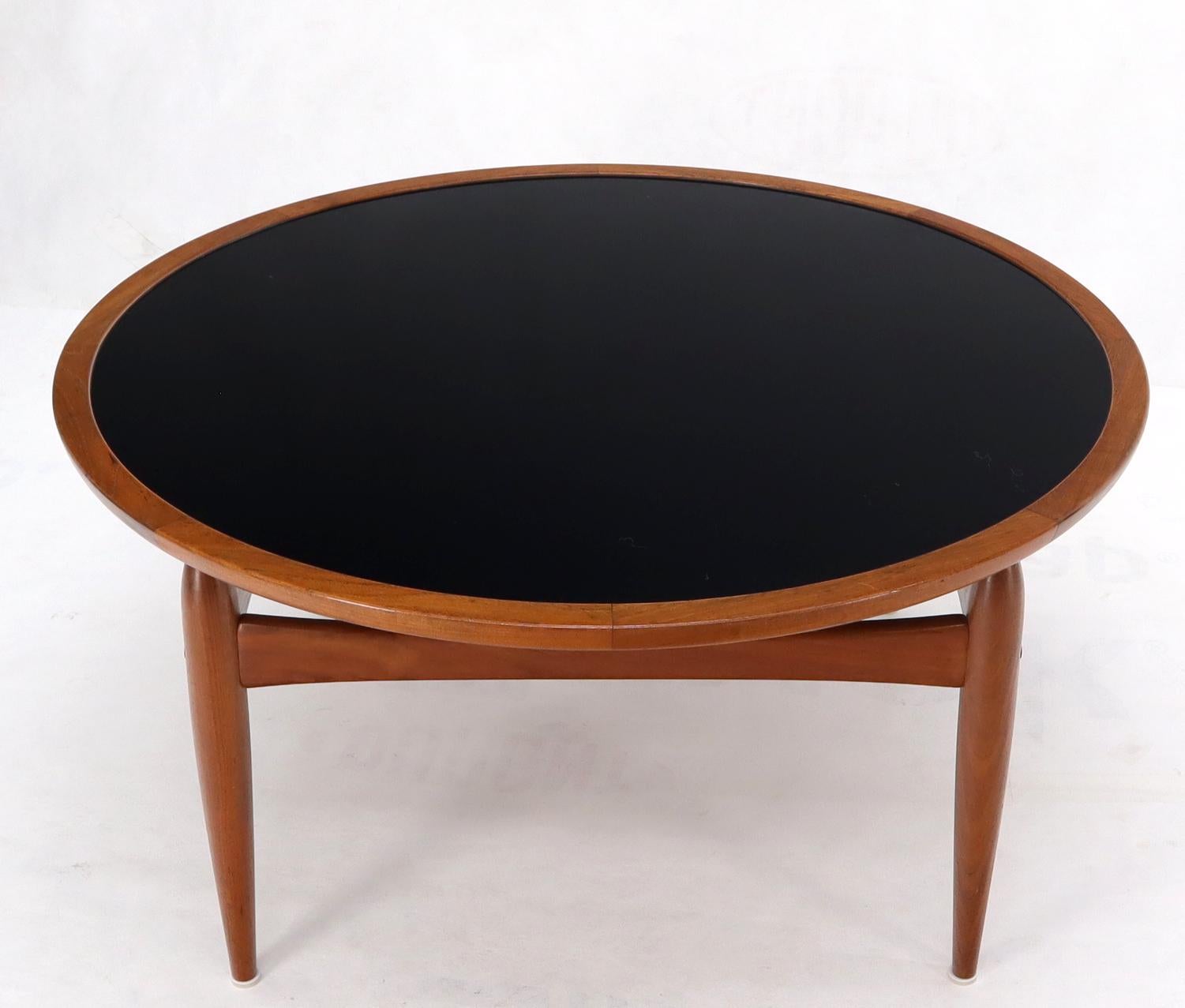 Mid century modern danish teak round coffee table with reversible top of exceptional quality. Durable black laminate waterproof option top, bullet shaped tapered legs.