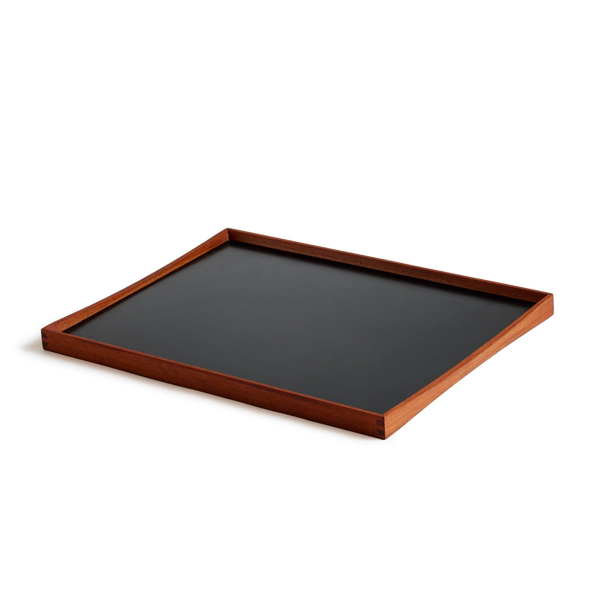 Una bandeja de servir reversible de laminado blanco y negro con marco de teca. Conocida como 