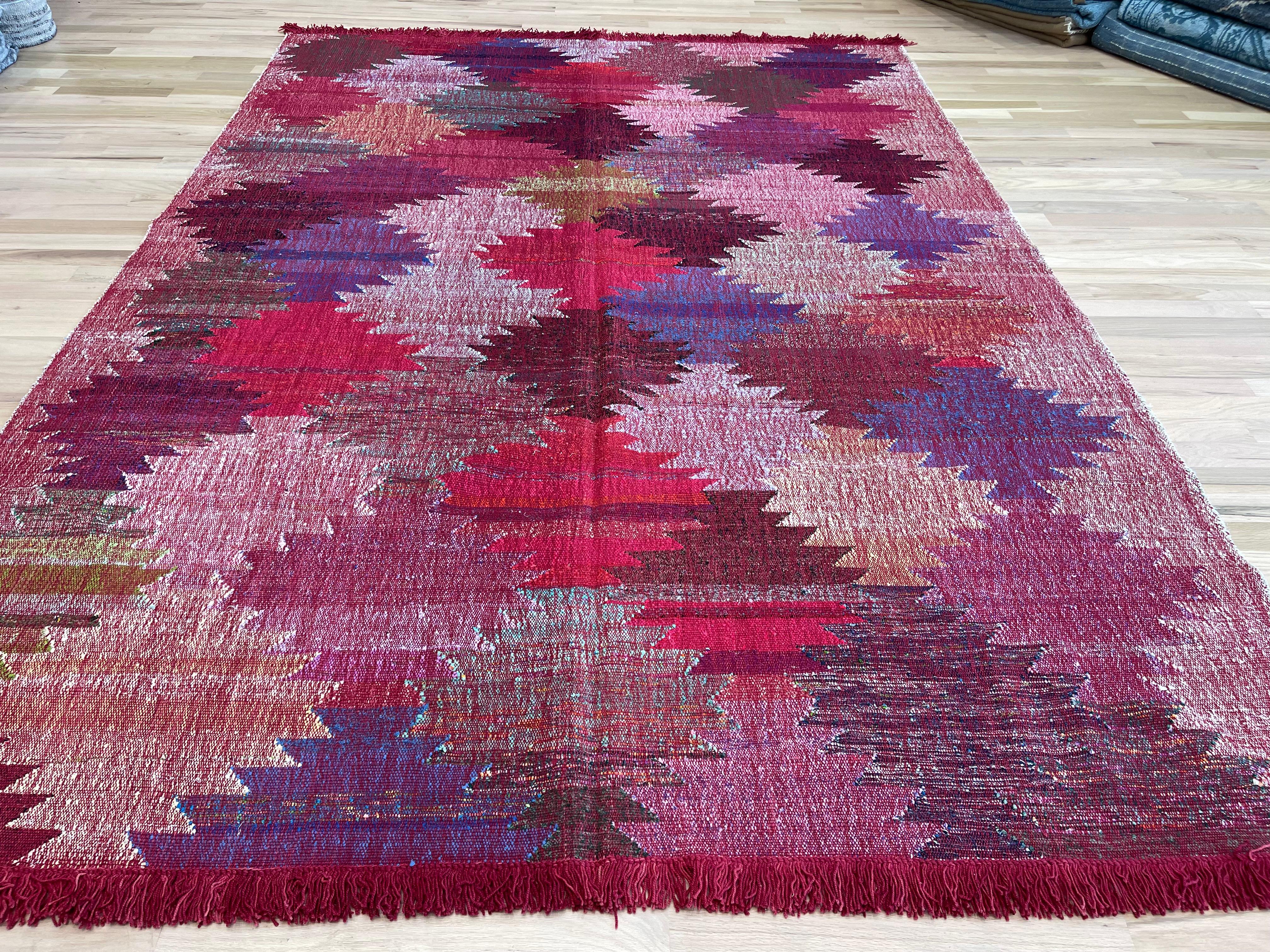 Rehaussez votre espace avec notre vibrant tapis turc. Avec une combinaison étonnante de roses, de rouges et de violets, ce kilim à tissage plat n'est pas seulement accrocheur, il est aussi réversible pour des options de style polyvalentes. Cette