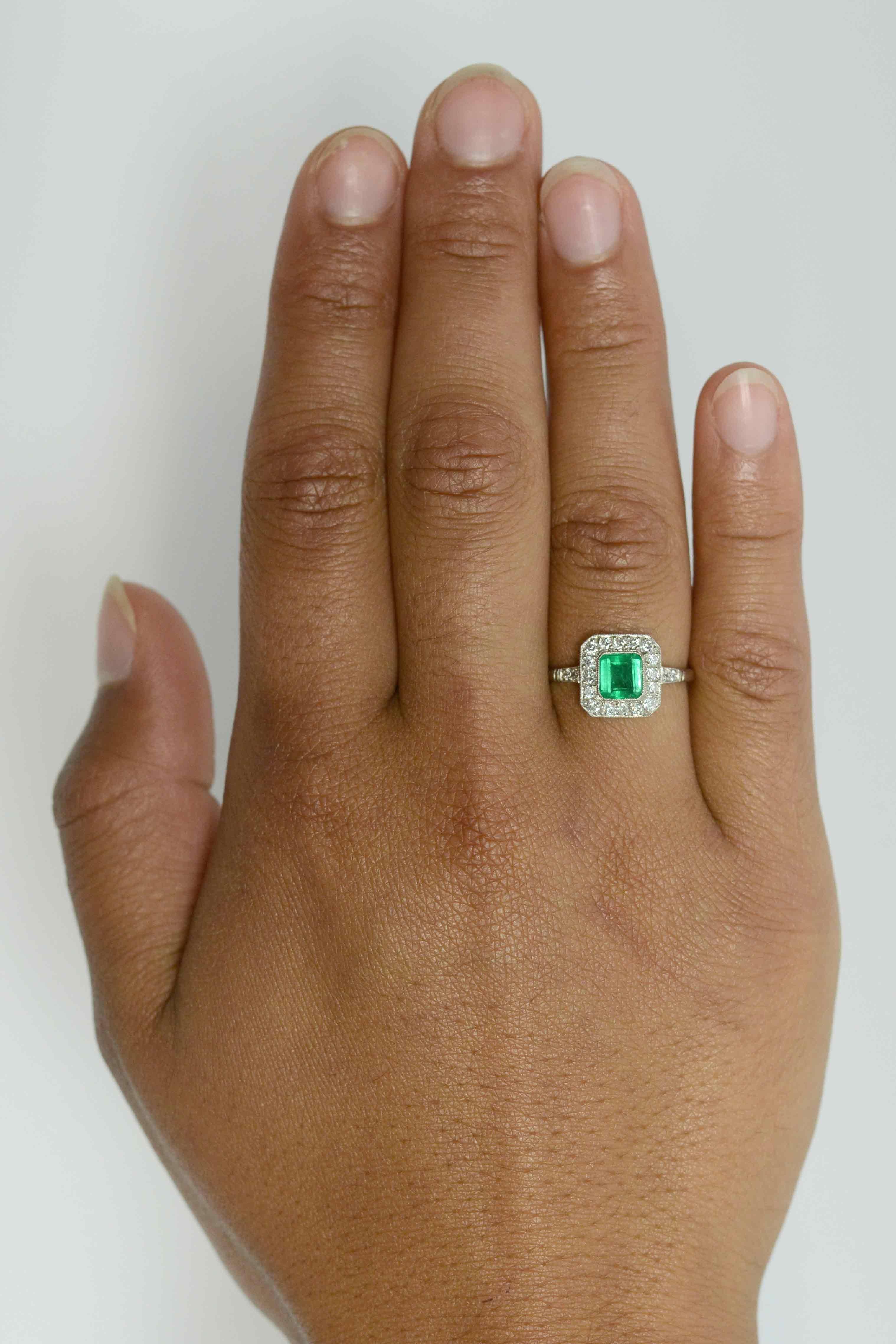 A breathtaking grass-green Colombian emerald takes center stage in this striking Art Deco Style engagement ring. The platinum setting features a 3/4 carat gemstone that glows with a light from within its soul. Floating in a bezel setting and
