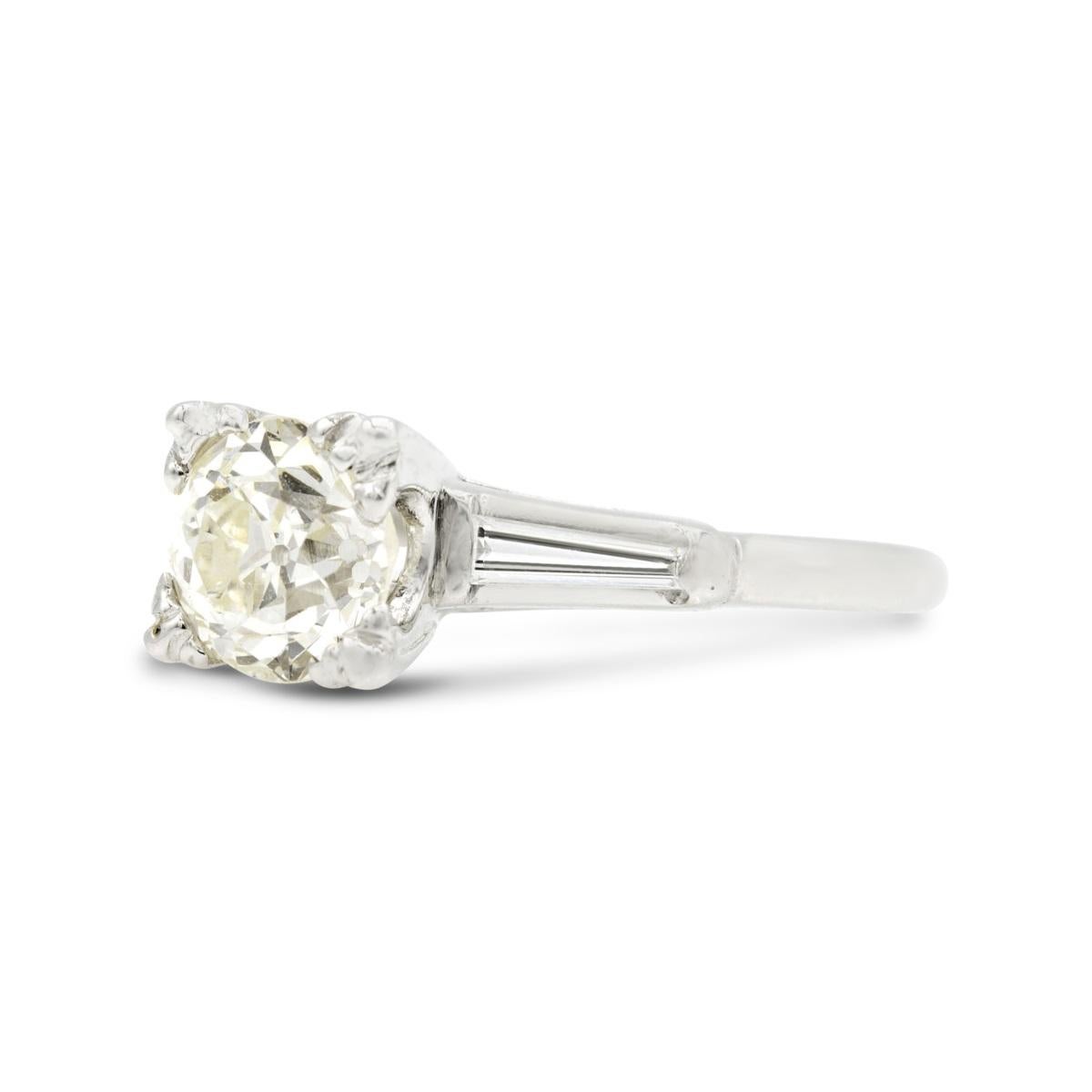 Sophisticated and chic, this timeless vintage engagement ring will charm her way into your heart. Just shy of 1.50 carats, the nearly flawless chunky Old European diamond at the center sparkles. Classic tapered diamond baguettes enhance the sleek