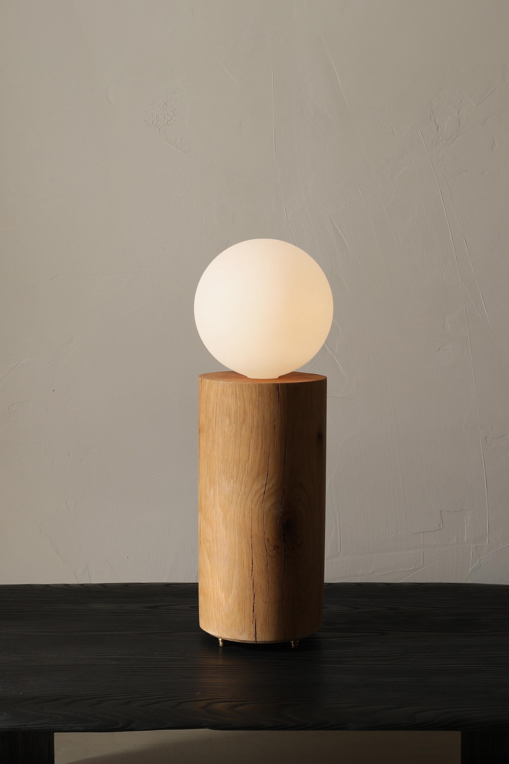 The Revolve Lamp is a solid oak table lamp with a large frosted globe bulb. The lamp sits on three bronze feet and is switched on the cord with a dimmer.

This piece comes from the Revolve collection - Graphic forms of this pedestal-based collection