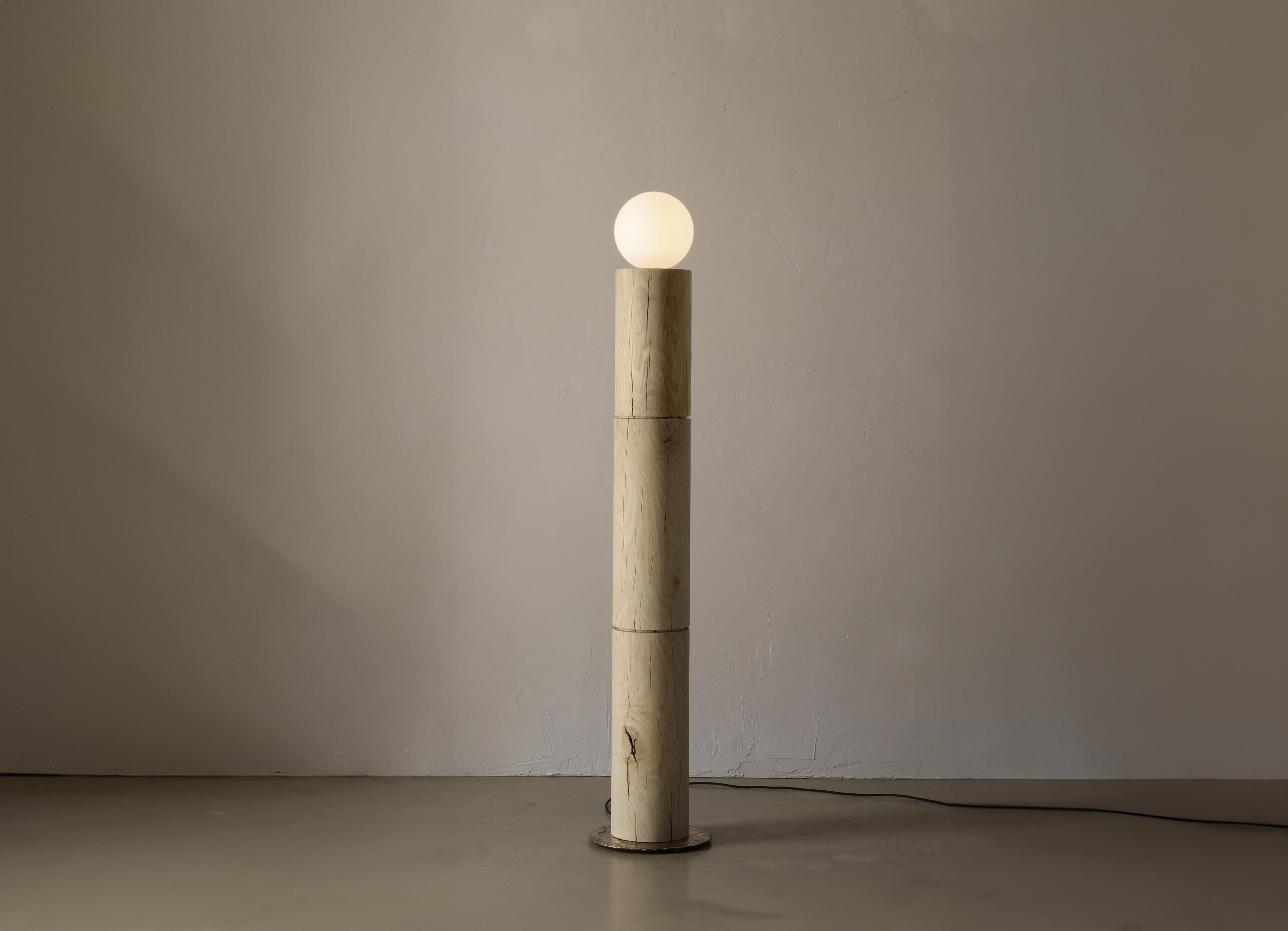 The Revolve Lamp II is a solid oak standing lamp with a large frosted globe bulb. The lamp a poured bronze plate and is switched on the cord with a dimmer.

This piece comes from the Revolve collection - Graphic forms of this pedestal-based
