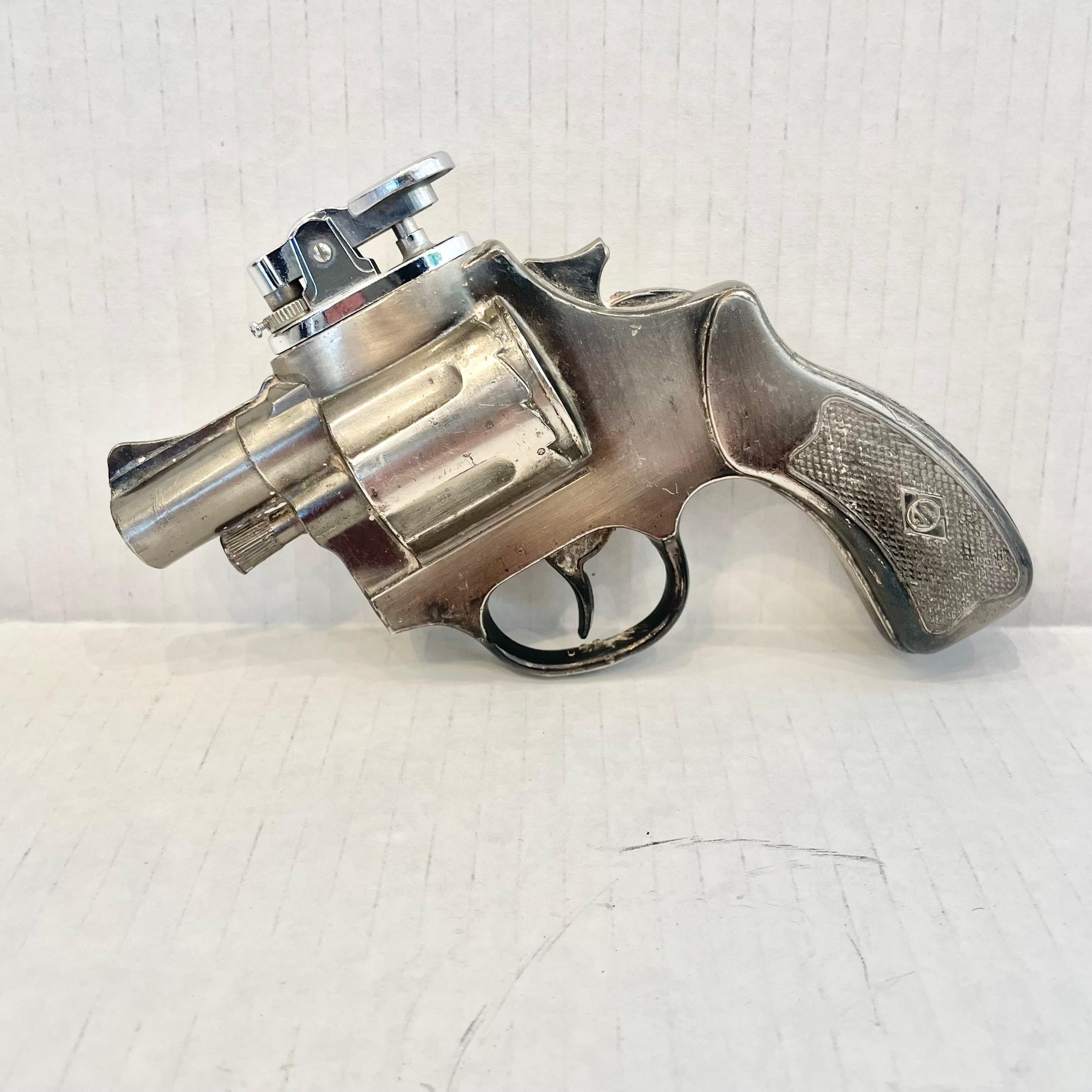 Cool vintage table lighter in the shape of a revolver. Made completely of metal with a hollow body. Classic silver color with beautiful details like a checkered grip. Cool tobacco accessory and conversation piece. Working lighter. Very unusual