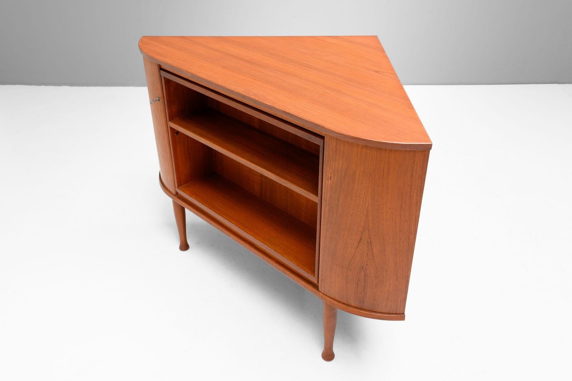 Mobile ad angolo in teak con libreria girevole e mobile bar a specchio nascosto, con contenitore per bottiglie e bicchieri con stelo dotato di serratura. Rifinito in ottime condizioni. Danimarca, circa 1960.
H. H. 113 cm x L. 113 cm x P. 66/89 cm
