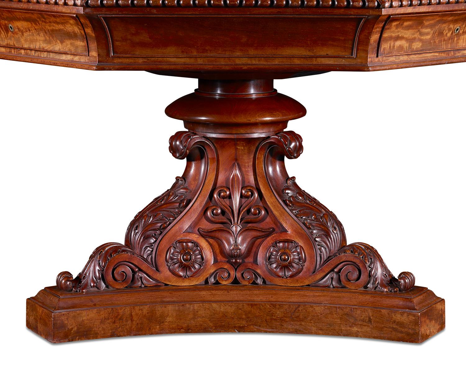 Almost certainly crafted by the legendary Gillows of Lancaster and London, this monumental mahogany library table is richly decorated. Its striking octagonal design features a rotating top covered in tooled leather and a pyramidal base adorned with