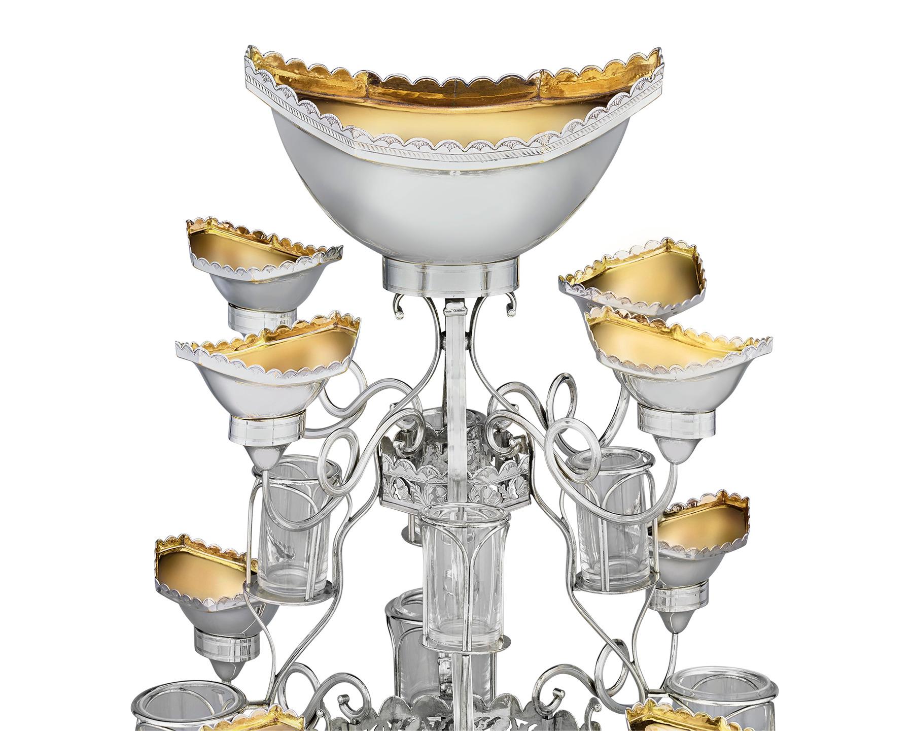 This Old Sheffield silver plate epergne showcases a refined Georgian-period scalloped motif embellished with acorns and foliage. It rotates with ease around its base for convenient access to all eight of its small dishes, cruet bottle holders and