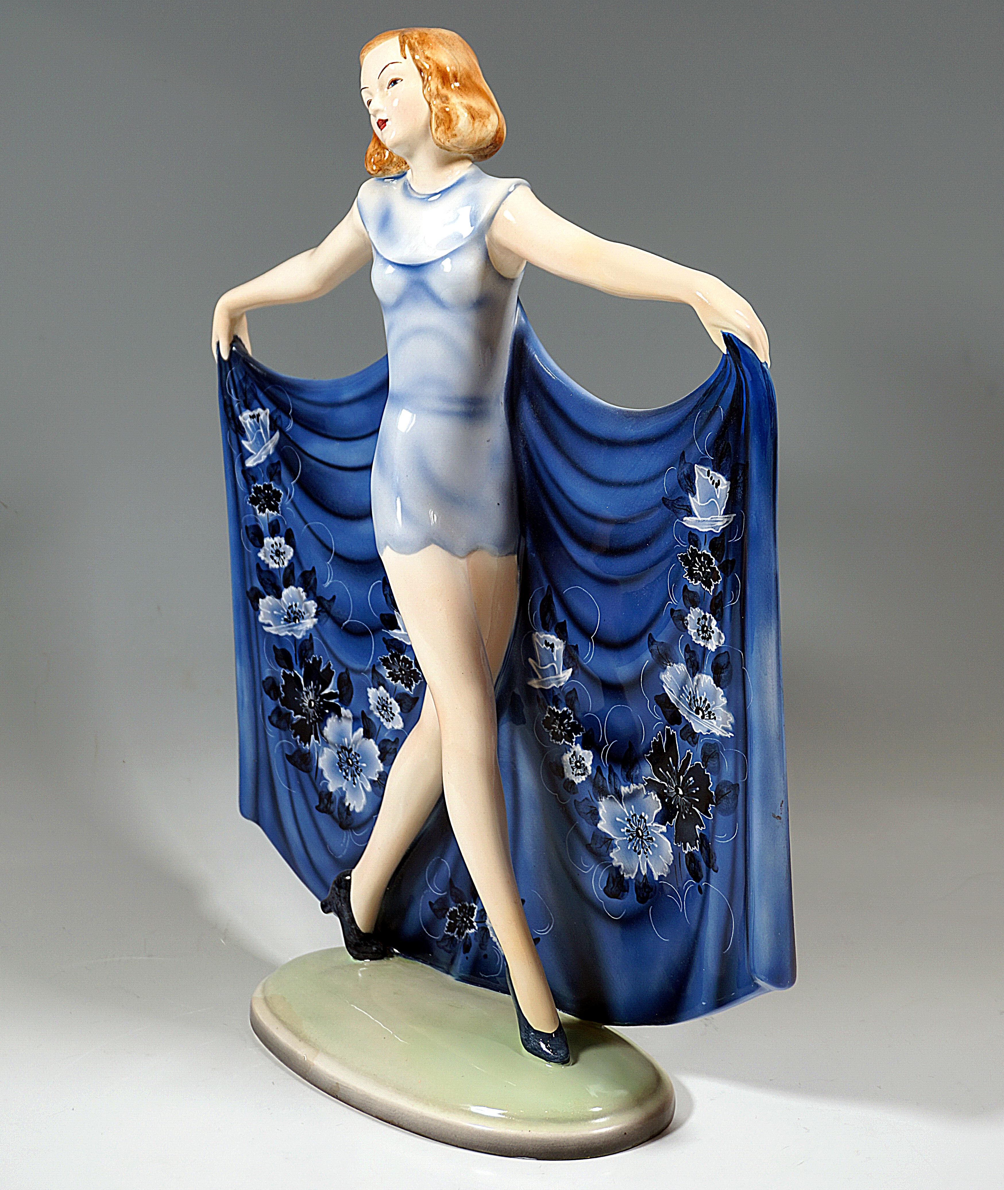 Rare Goldscheider Art Deco Ceramic Figure Of The 1930: 
Young dancer with chin-length, dark blonde hair in a form-fitting, short, light-blue dress with a long train attached to the back with white-blue floral decoration, holding it up on both sides