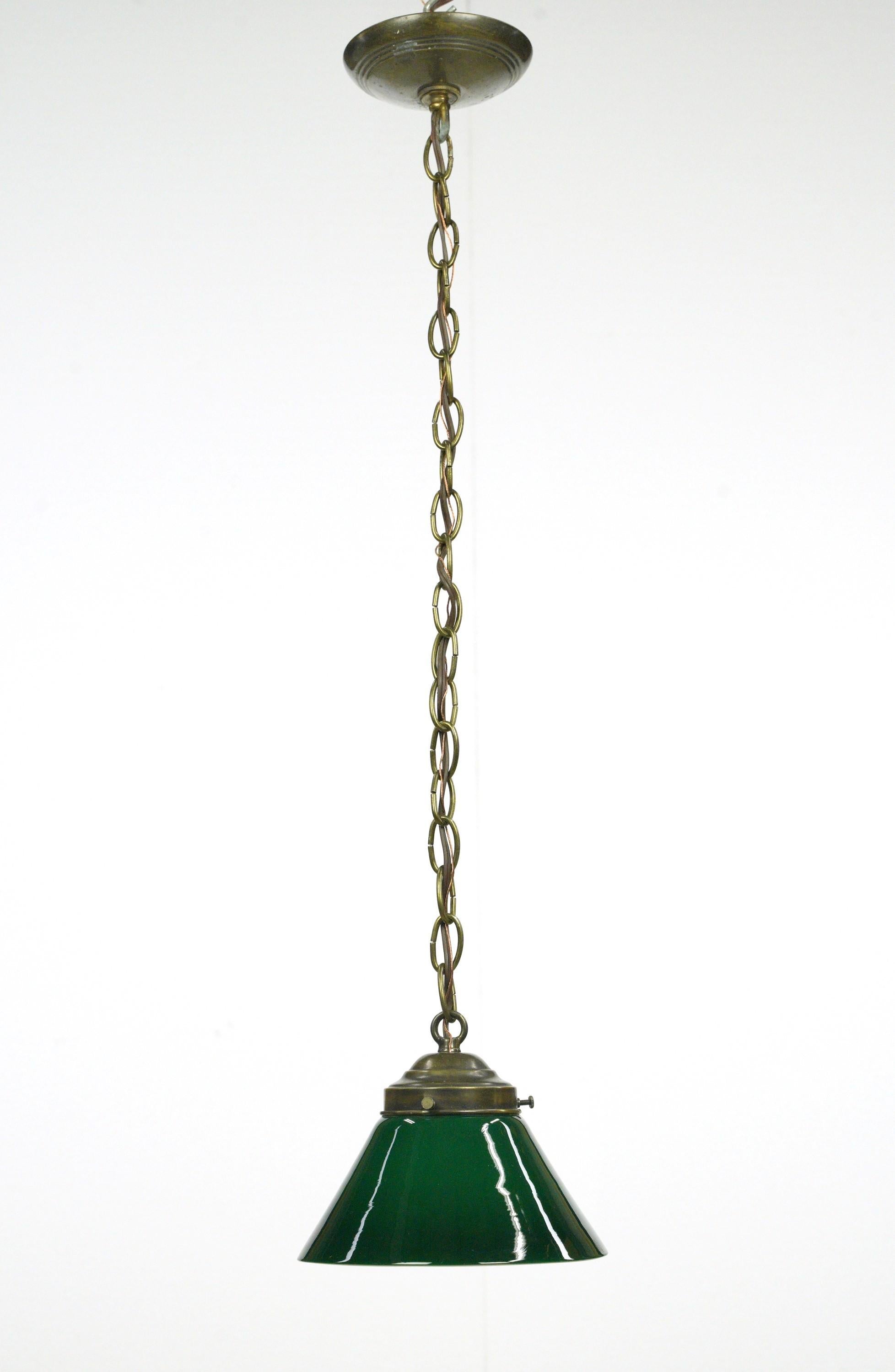 Pendant light with a green glass shade and a brass chain fitter. This requires one standard medium base bulb. The price includes restoration of cleaning and rewiring. Good condition with appropriate wear from age. One available. Cleaned and