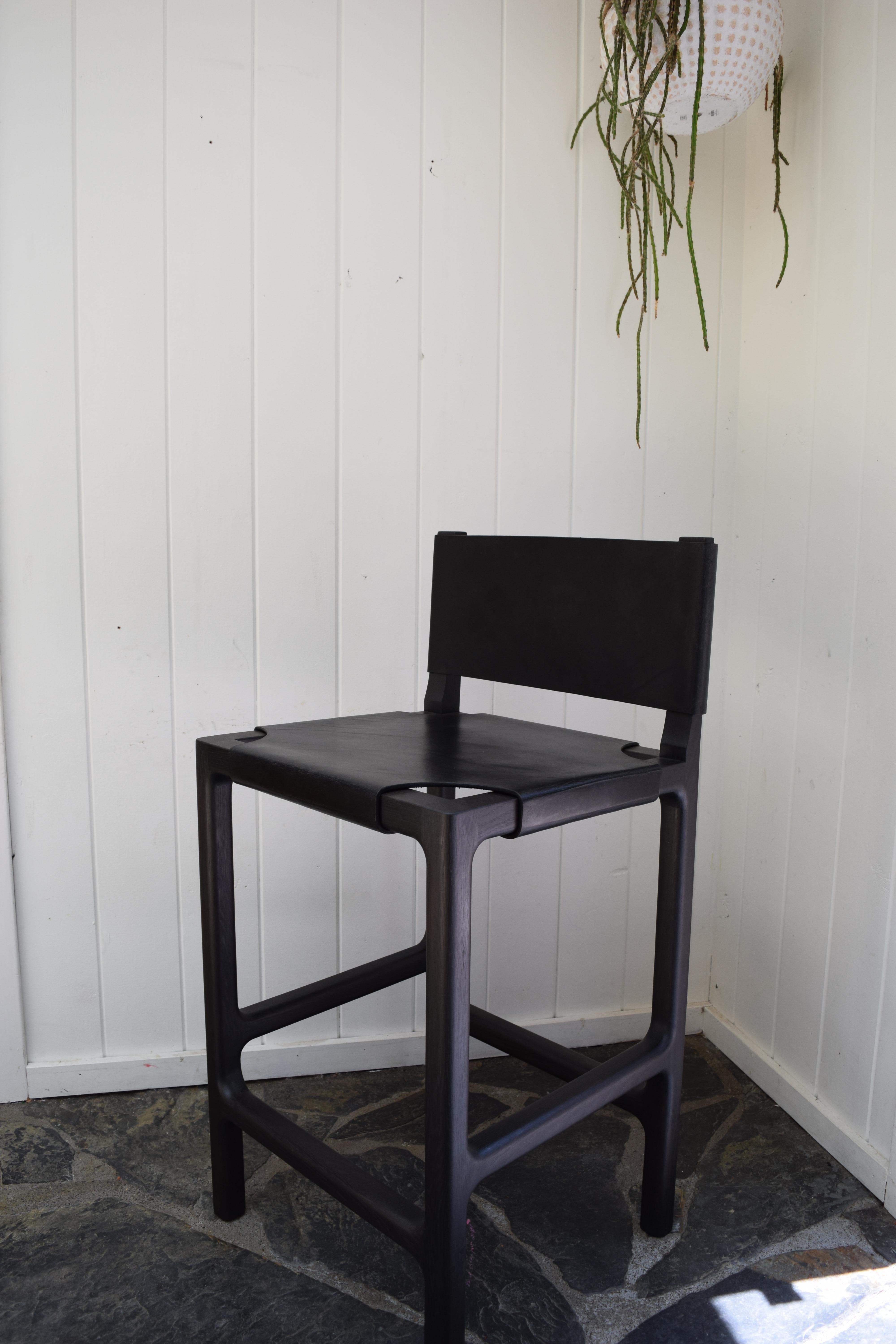 This is an ebonized counter stool with a stretched leather seat and back. The frame is solid oak with a gentle radius at the interior joints and softly rounded edges. The leather is 10 oz vegetable tanned leather that has been stretched across the