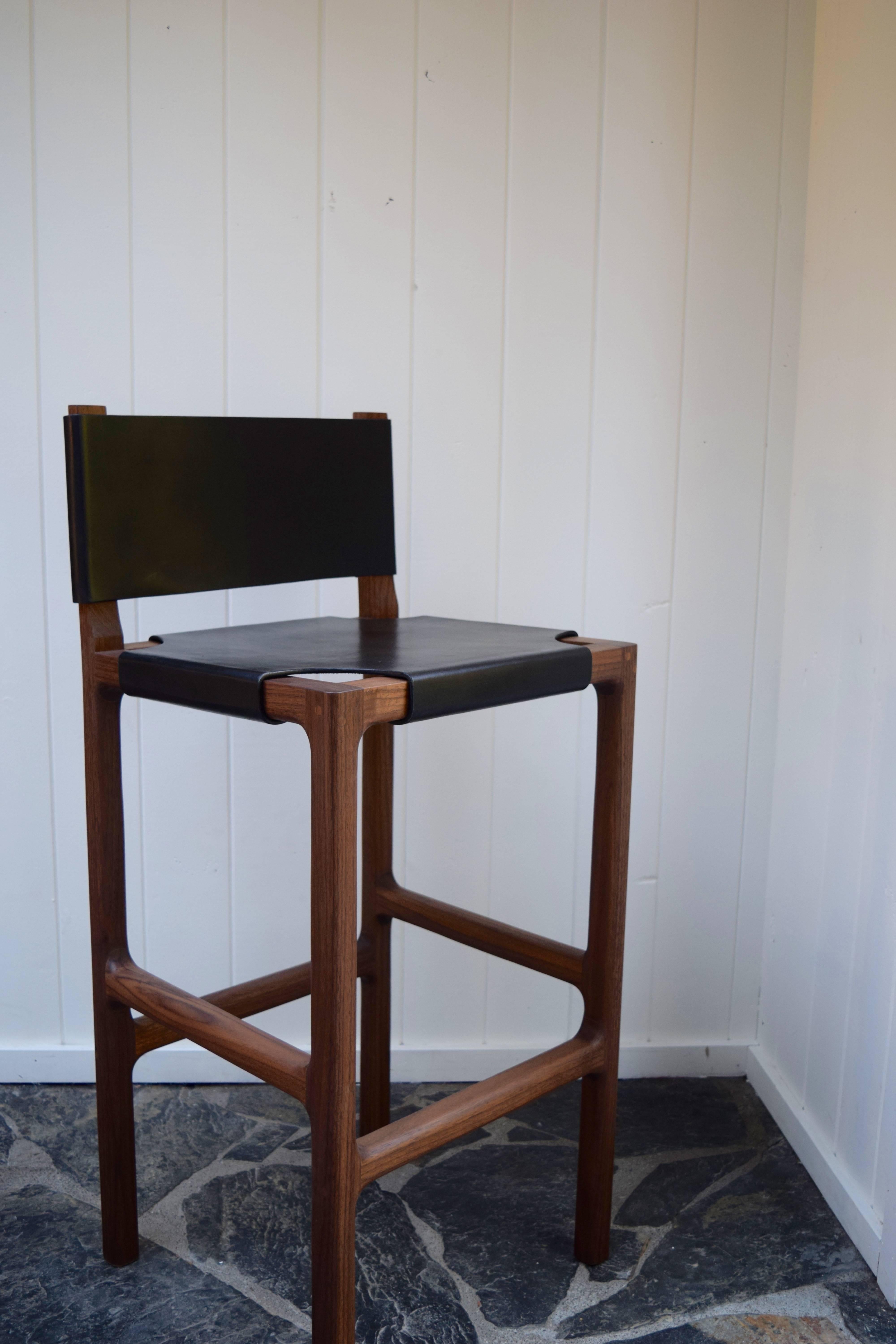 This is a walnut counter stool with a stretched leather seat and back. The frame is solid walnut with a gentle radius at the interior joints and softly rounded edges. The leather is 10 oz vegetable tanned leather that has been stretched across the