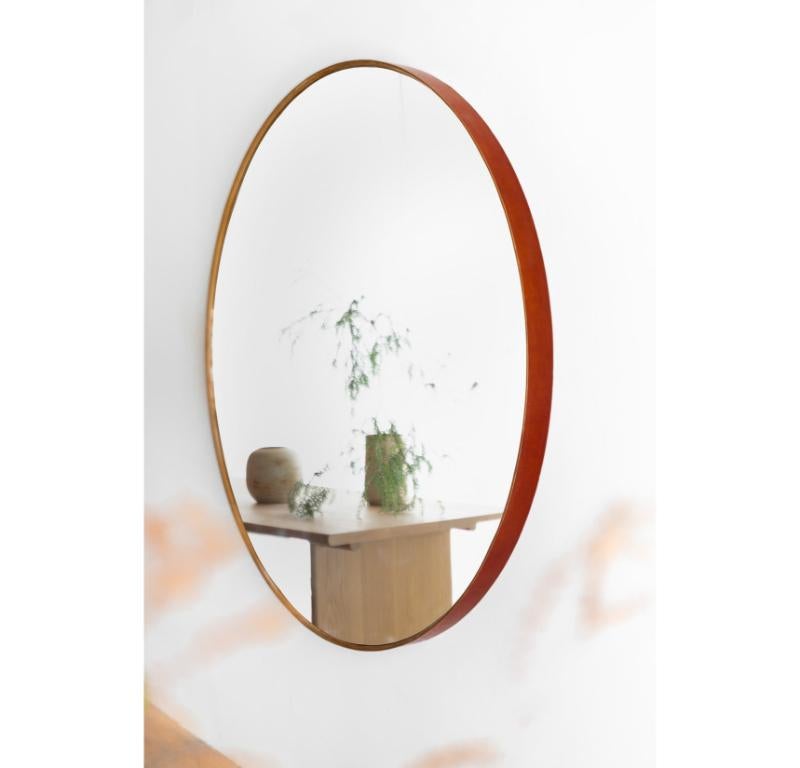 Le miroir mural Reyes est fabriqué à la main à Los Angeles, en Californie. Le cadre en bois est moulé sur mesure et enveloppé de cuir tanné végétal. Le miroir est fixé au mur à l'aide d'un système de tasseaux à la française pour un aspect propre et