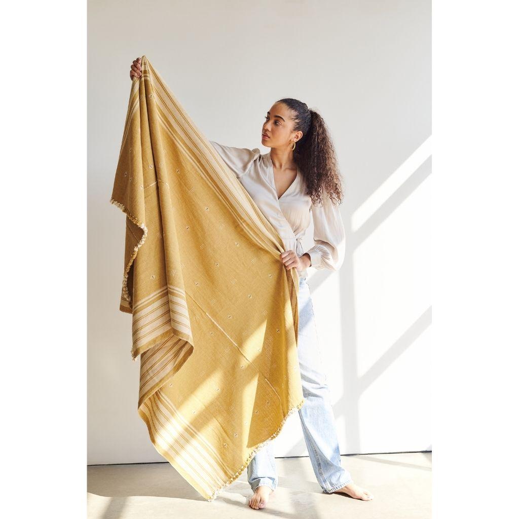 Reyti Ochre Throw is a 100% organic cotton throw woven by improvising an ancient technique of handloom weaving originating from Western part of India. Reyti means mud / sand in Hindi language, and this particular throw with its natural dye gives an