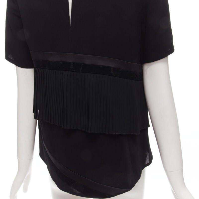 RHIE - top in velluto satinato nero con volant plissettato US2 S
Riferimento: KNLM/A00032
Marchio: Rhie
Materiale: Viscosa
Colore: nero
Modello: Tinta unita
Chiusura: bottone a pressione
Fodera:  Poliestere
Dettagli extra: Profili in raso e velluto.