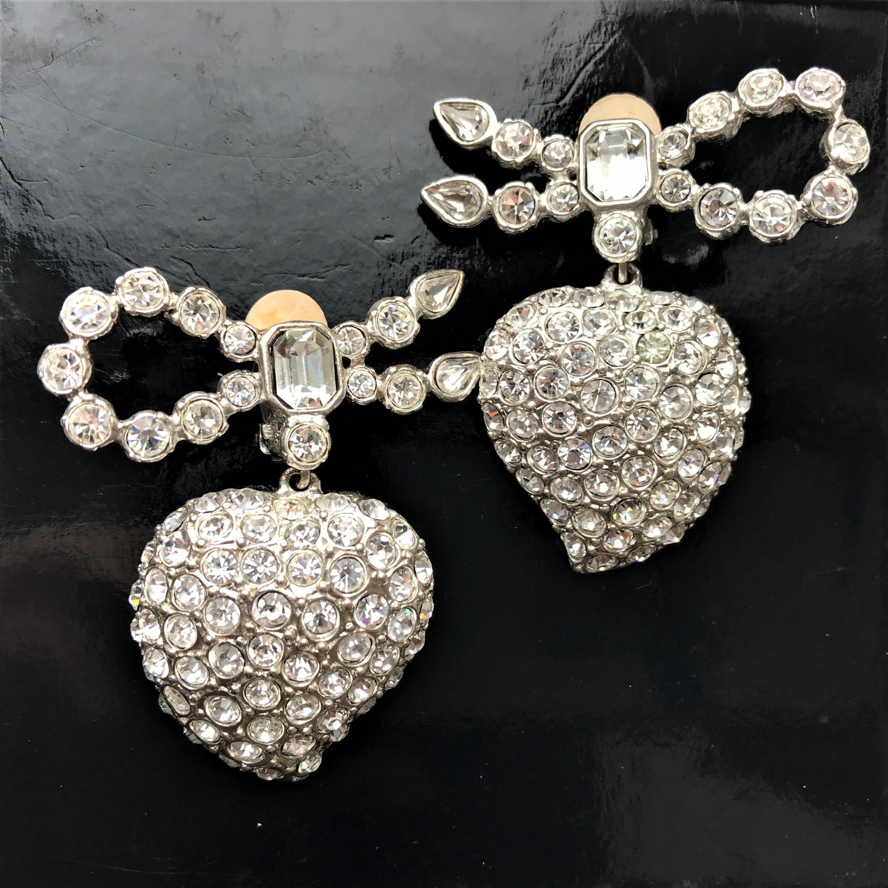 
Very stylish ear clips by Yves St Laurent. A beautiful heart hangs on a bow. The bow and heart are entirely set with cut rhinestones. In the middle of the loop a large square cut rhinestone. 
Measurement:  Length of the ear clip 5 cm, bow Width 4