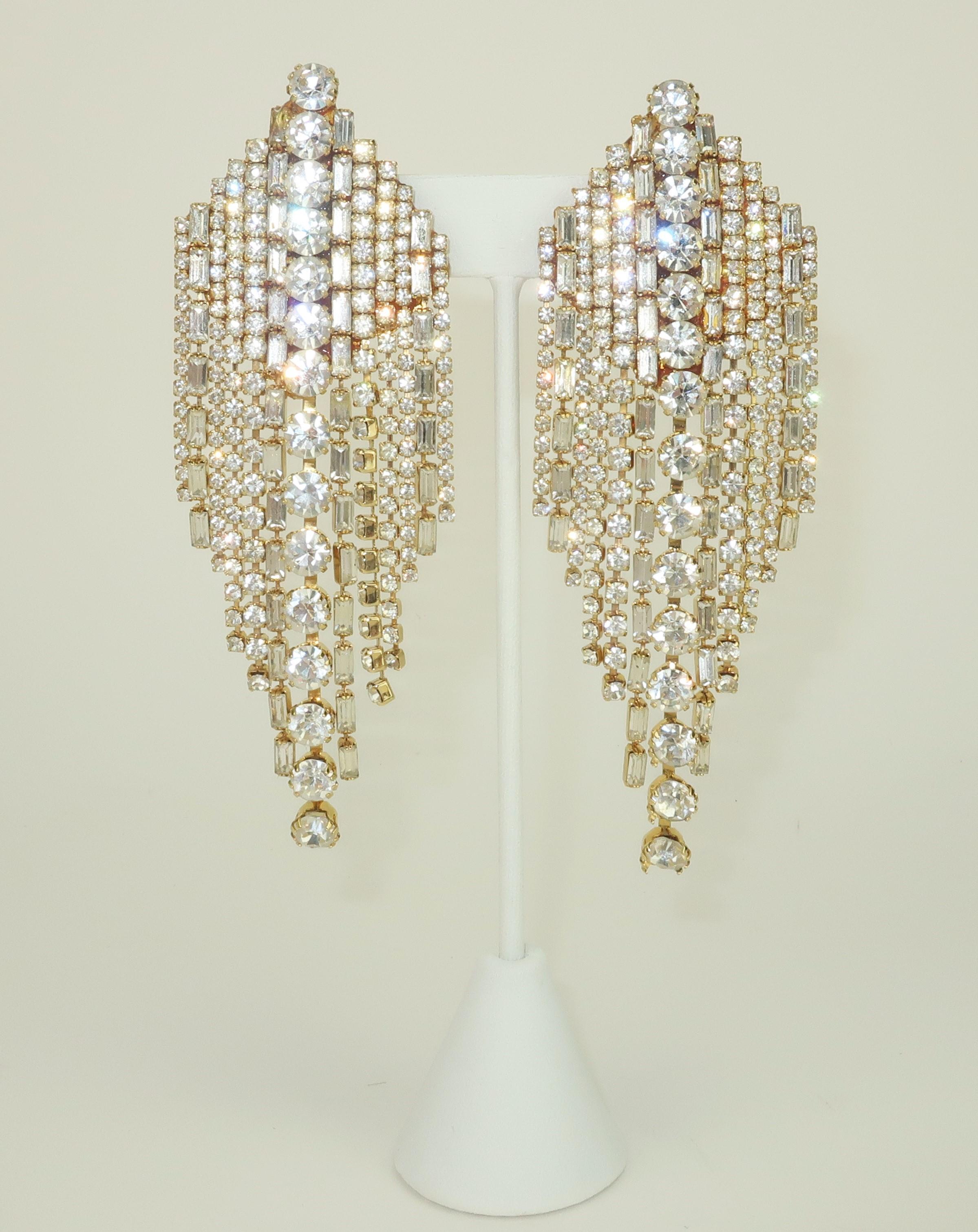 1980's crystal rhinestone clip on earrings with a glamorous waterfall silhouette and a nod to Art Deco revival design.  The statement making earrings are designed with rows of rhinestones in varying shapes chained together to form dangles with loads