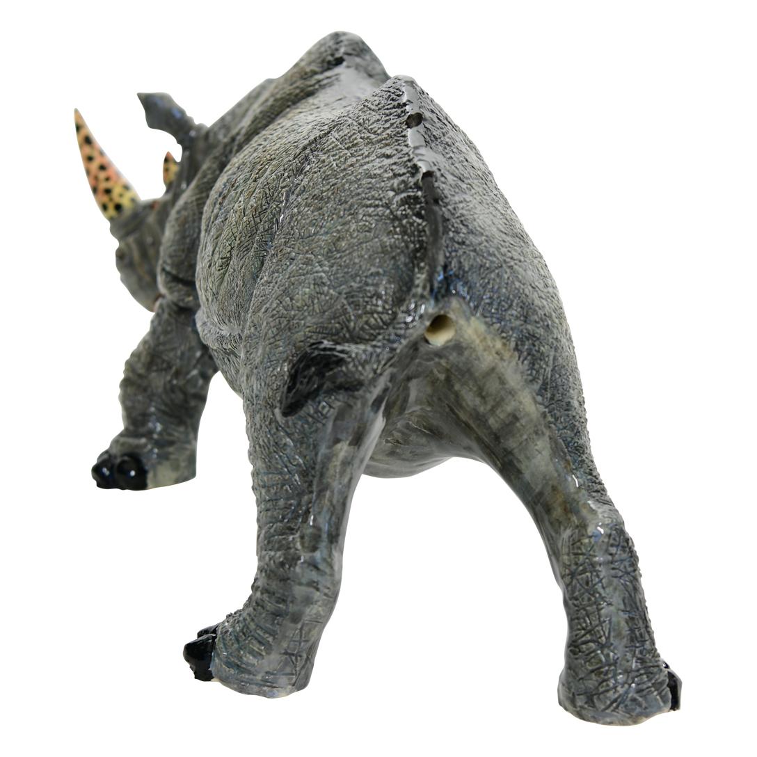 This Rhino Sculpture was hand sculpted by the renowned artisan Sondelani Ntshalintshali and beautifully painted by Minenhle Nene both from South Africa. This exquisite ceramic creation stands 8 inches high, measuring 18.5 inches in length and 7