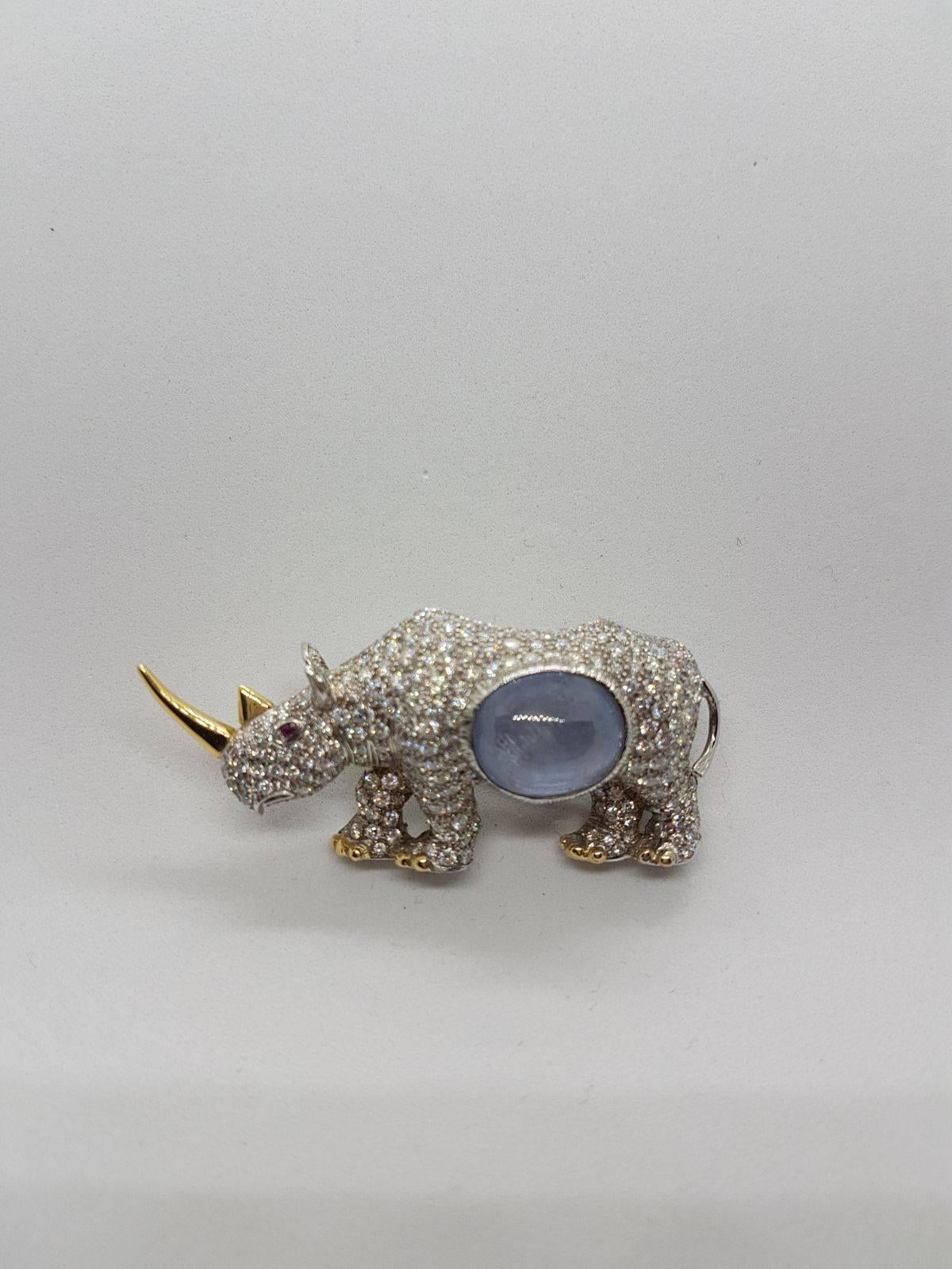 Handcrafted Broach in the shape of a Rhinoceros in 18 kt White and Yellow Gold with 5.75 Carats of Diamonds and one natural Blue Sapphire 15.47 Carats Cabochon