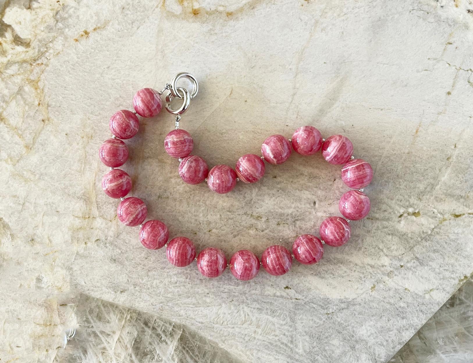 This is a truly spectacular top quality natural rhodochrosite necklace comprised of 19mm round natural rhodochrosite beads, sterling silver accent beads, and an elegant interlocking clasp. We love this clasp style. It is so easy to fasten on your