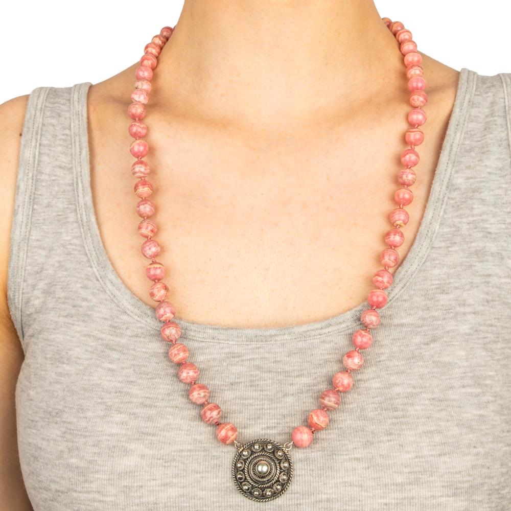 Distinctive necklace consisting of sixty five natural rhodochrosite beads attached to a filigree silver pendant, with a silver clasp. 

20th century

28 in. (71.1 cm.) long, the pendant, 1 ¼ in. (3.2 cm.) diam.   

Found in Russia and elsewhere,