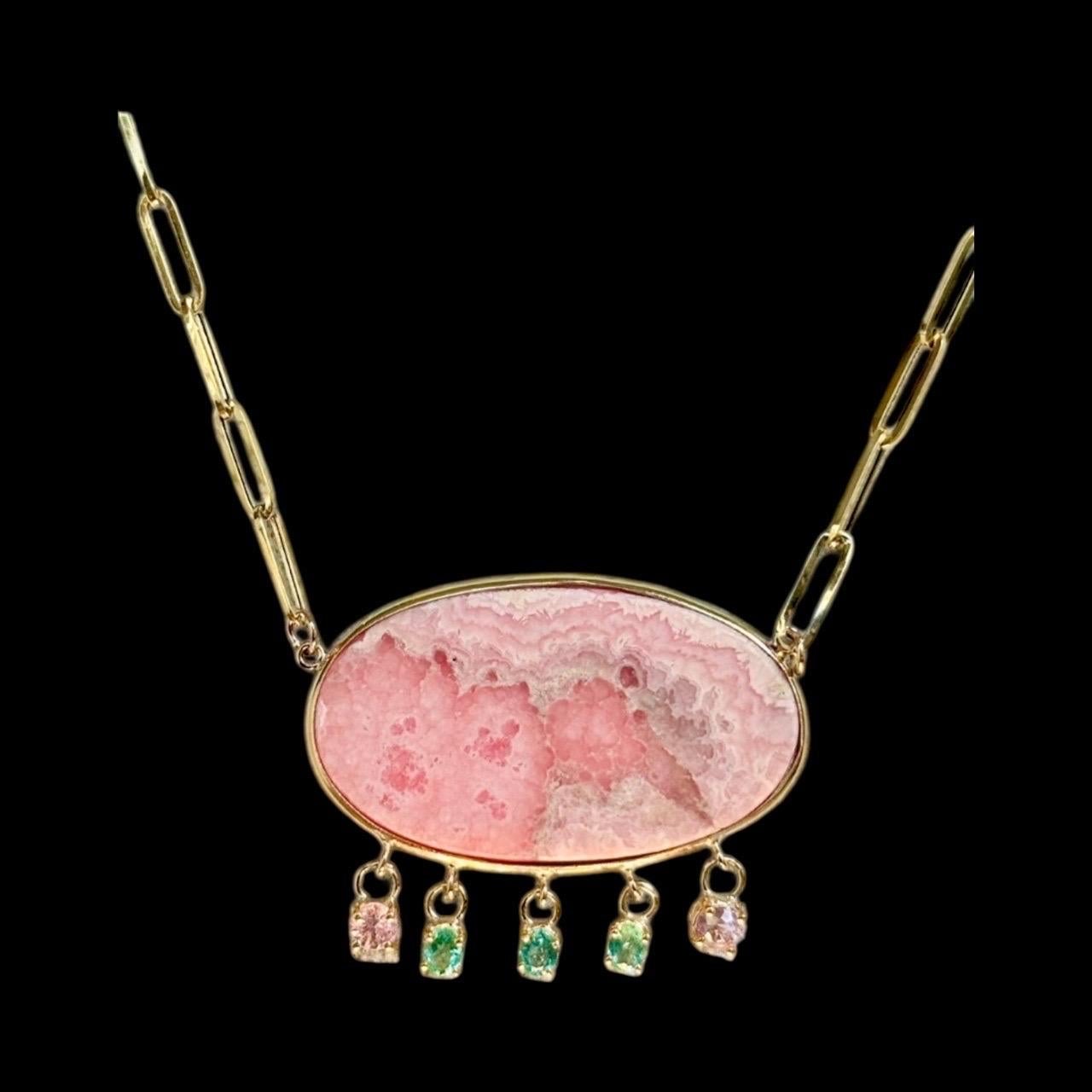 Rhodochrosite Necklace with Emeralds and Pink on Paperclip Chain

Rhodochrosite, Emeralds, Pink Spinel & 14k Gold 

Center Rhodochrosite (1.25” in length) bezeled in 14k gold with three dangling oval emeralds flanked by two dangling baby pink round