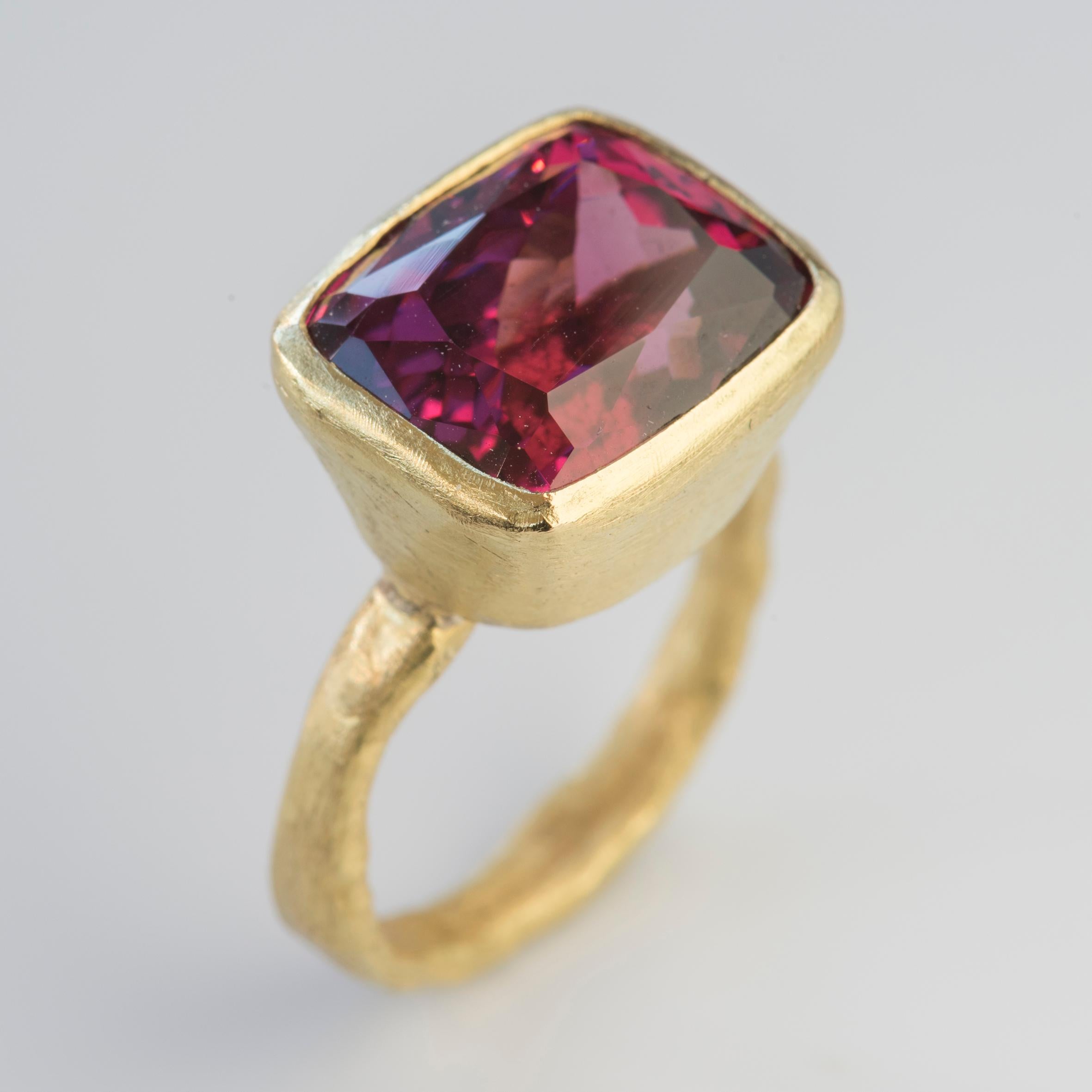 18k yellow gold organic textured ring with stunning Rhodolite Garnet, rectangular cushion cut 13.78 carats.
The colour of this Rhodolite Garnet is rich and vibrant, flashing scarlet, fuchsia and raspberry depending on the light. 
Disa Allsopp is