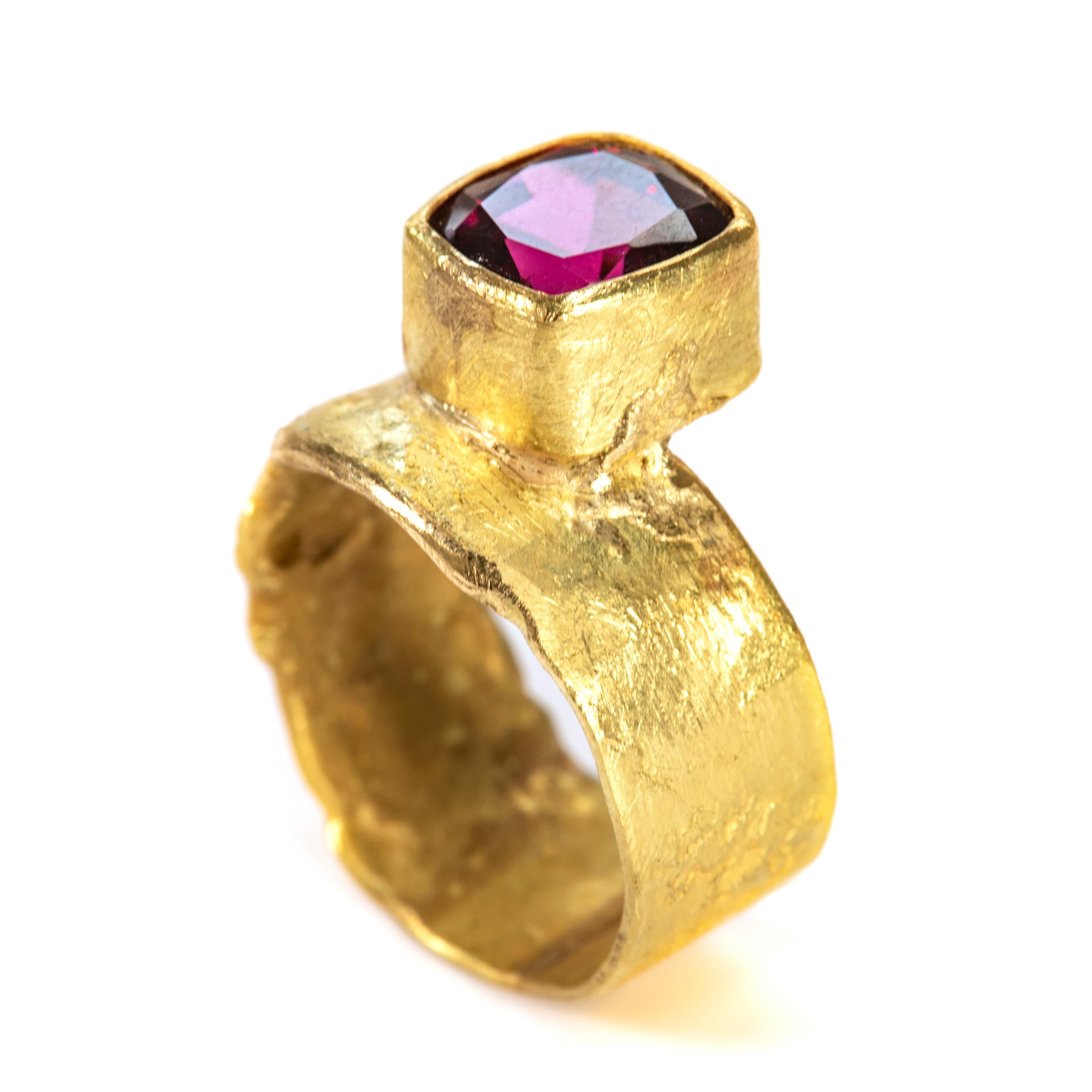 18k gold wide organic ring with cushion cut Kenyan Rhodolite Garnet. The stone is 3.56cts and the band is 9mm wide,  The ring features a tapered rub over setting to enhance and frame the stone.

Disa Allsopp handmakes each ring using traditional