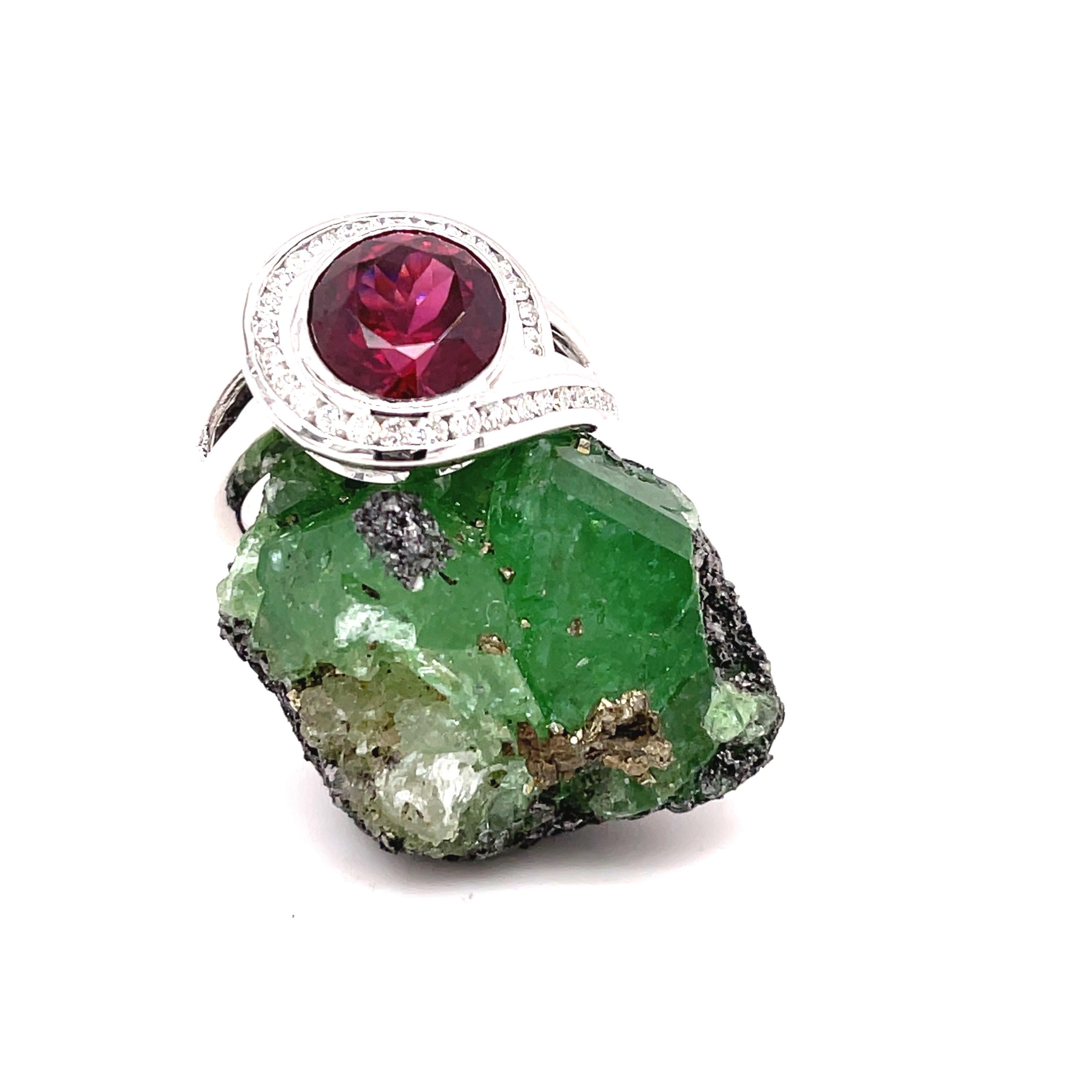  This Rhodolite Garnet came from East Africa and was cut in the Vance Gems shop into a 9.4 mm round portuguese cut weighing 4.18 carats. 
The ring has a unique split shank and the top of the ring is designed to give the stone some light. It was made