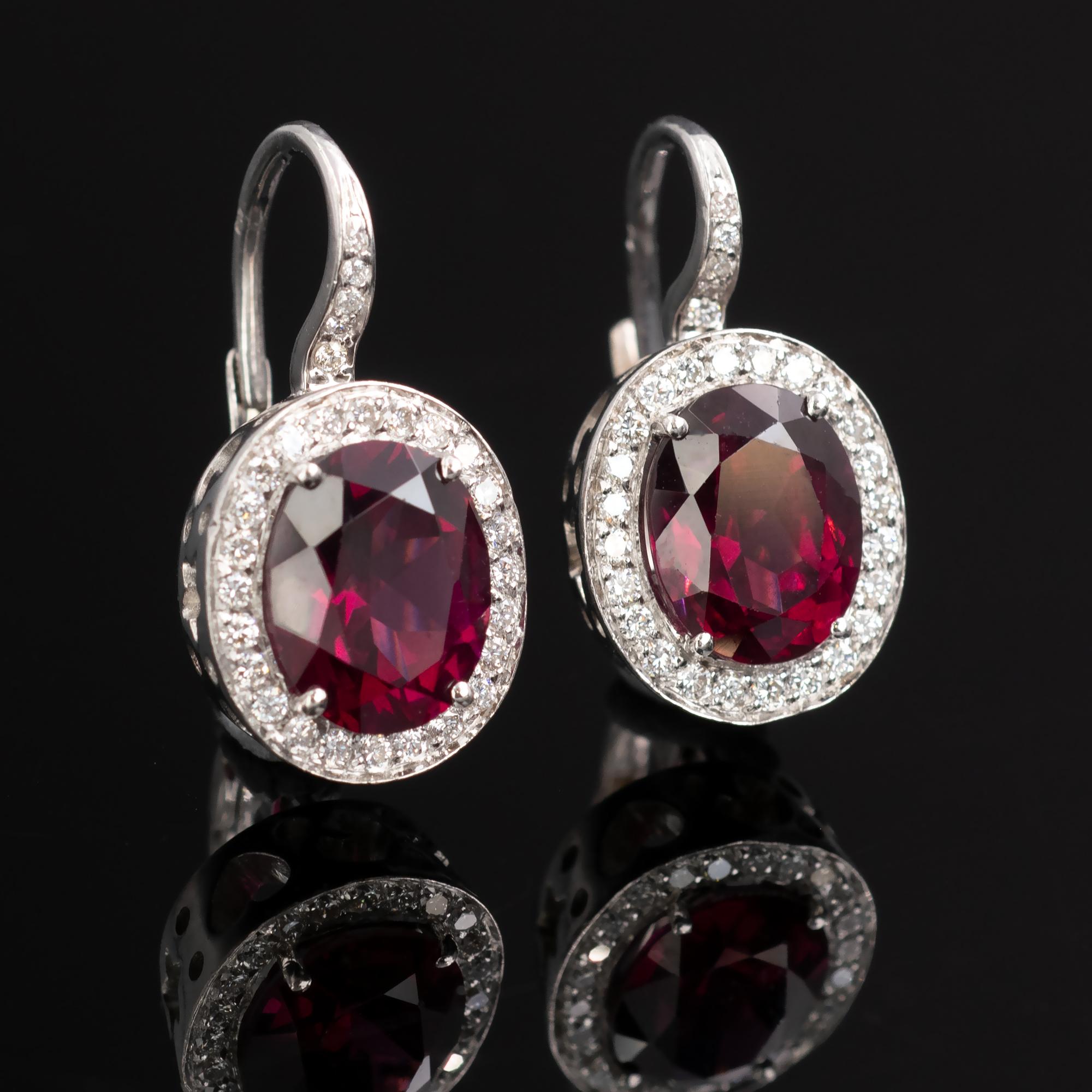 Lively oval rhodolite garnet with halo diamonds around on 18 Karat white gold.
The sides of the earrings are decorated with stars, hearts, and moon crescent cut-outs. 
The make is excellent, which gives these trendy earrings a very pleasant hefty