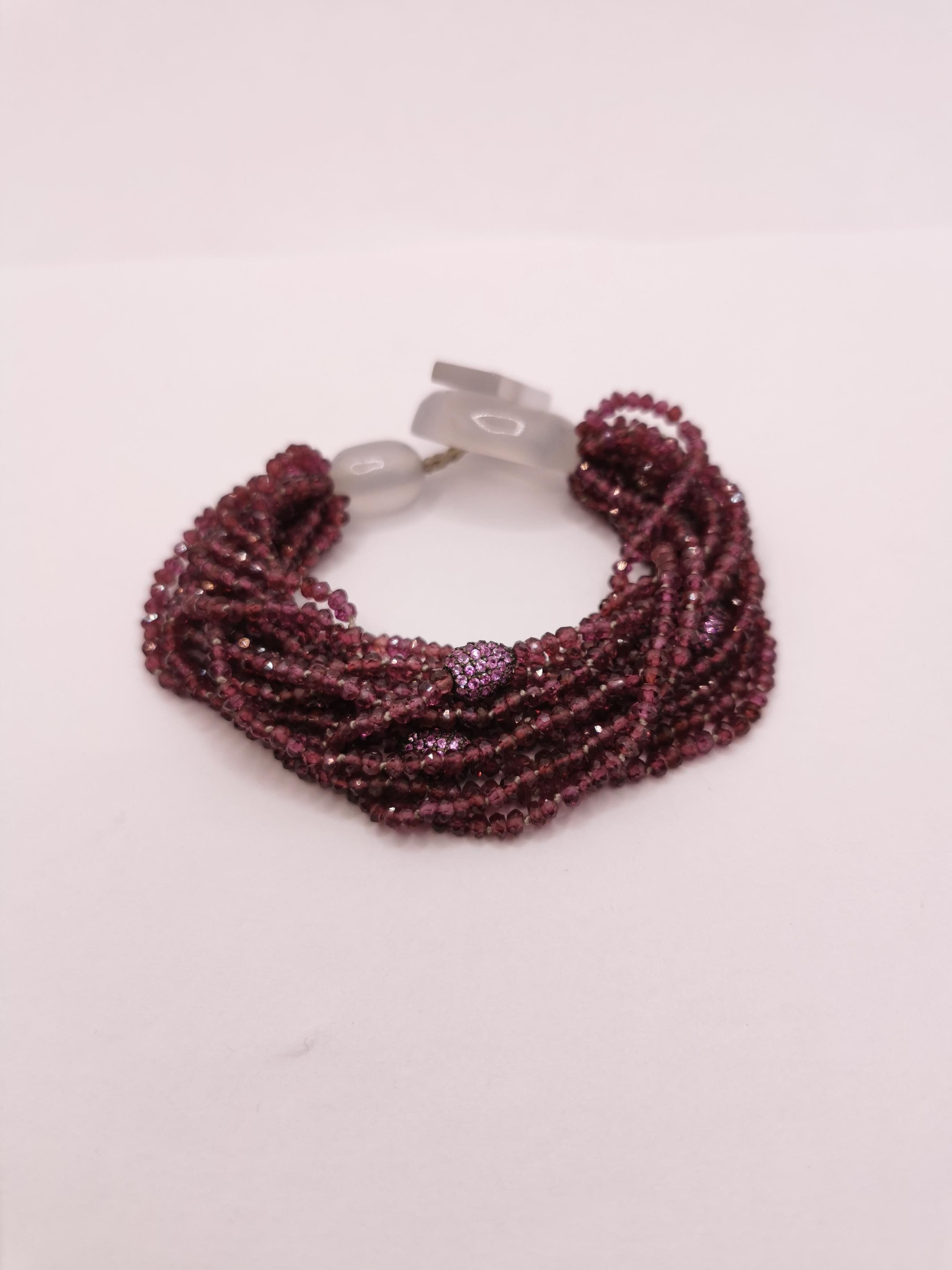 This is a beautiful bracelet made of few wires of briolet cut Rhodolite.

Among someone wires, are placed four oval elements embellished with Pink Sapphires that gives to the bracelet lightness and a touch of elegance.

The closure is made by two