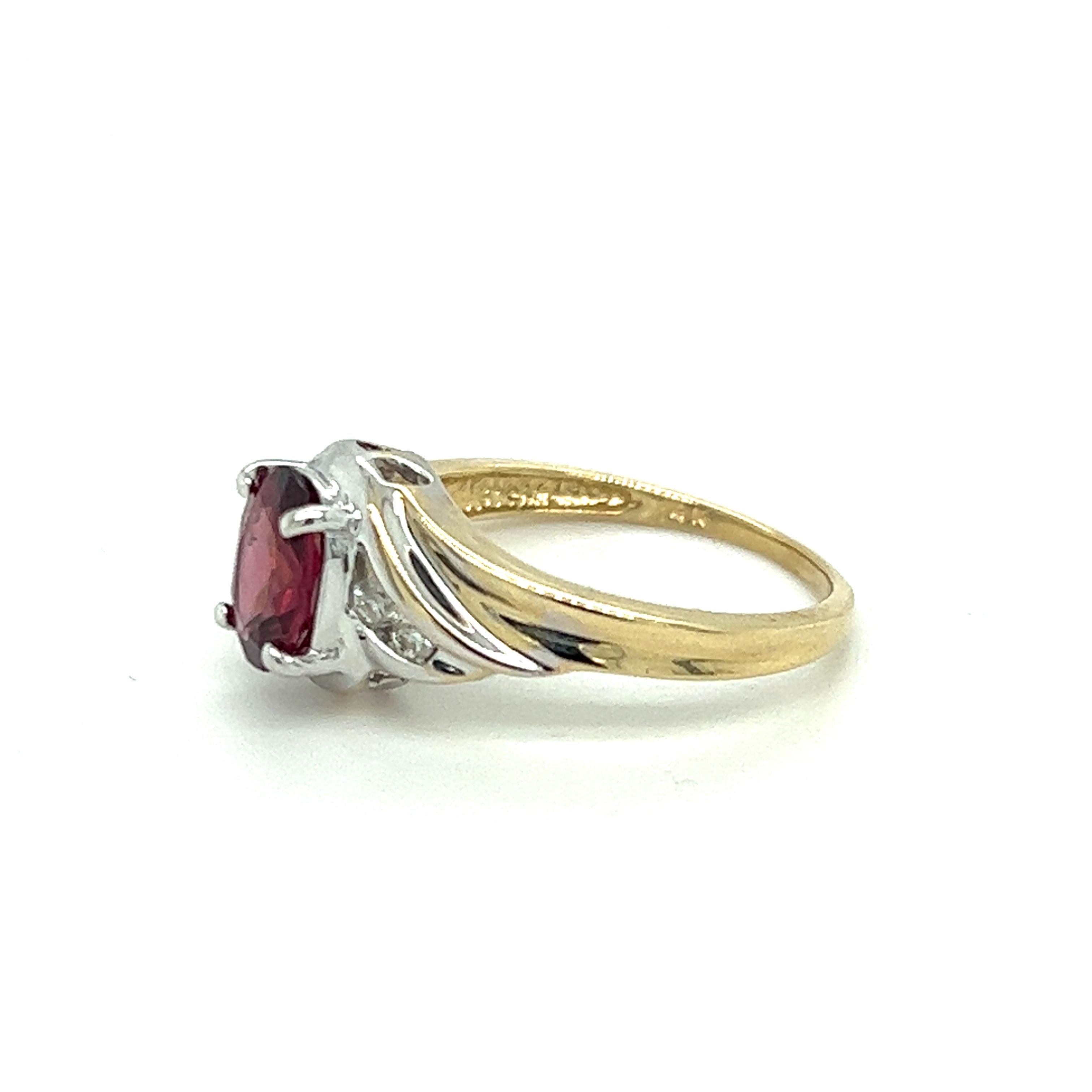 One 14 karat yellow and white gold ring set with one 8x6mm oval rhodolite garnet and 4 brilliant cut diamonds, approximately  0.12 carat total weight with matching I/J color and I1 diamonds.  The ring is a finger size 7.75 and can be resized. Sizing
