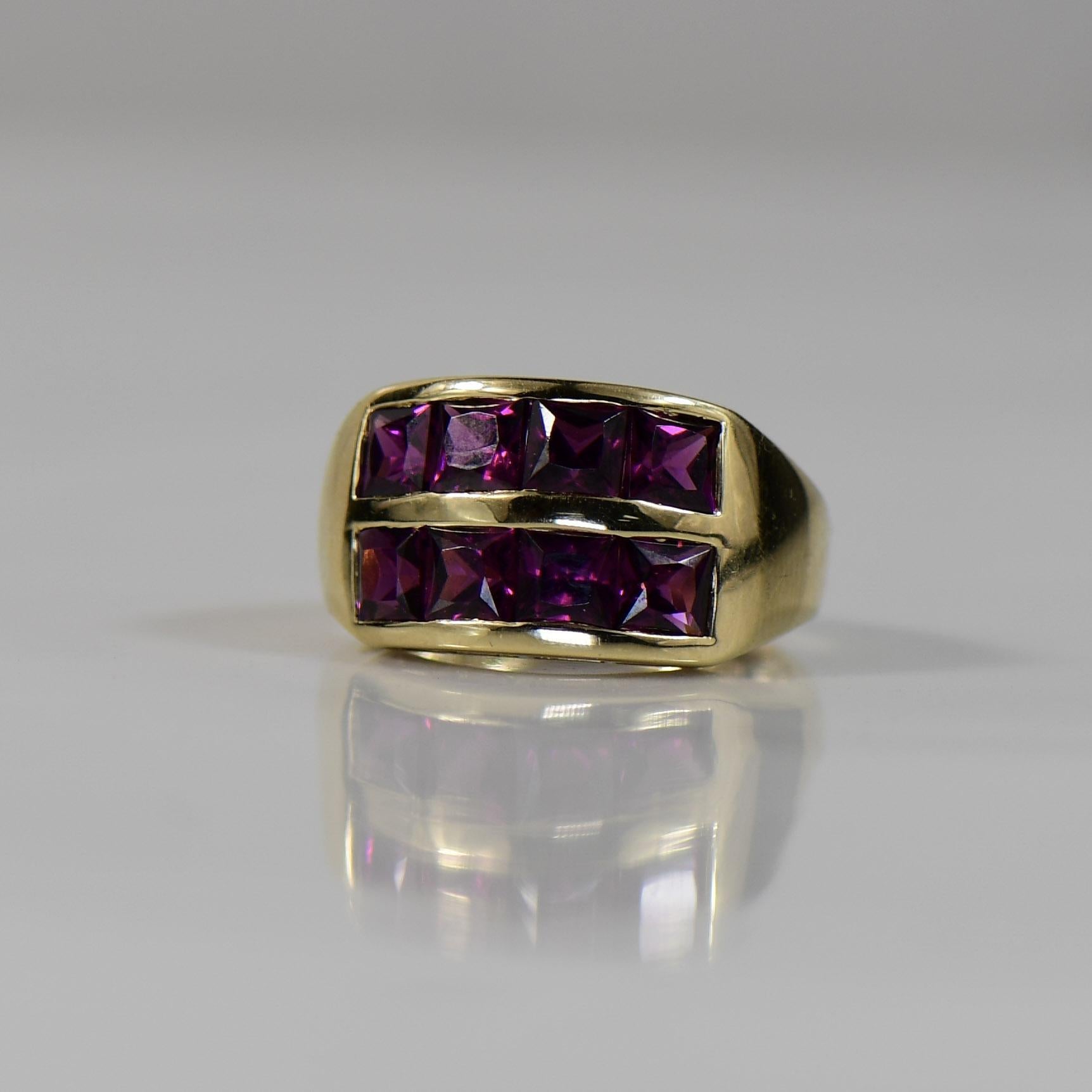 Dieser Ring aus prächtigem 14-karätigem Gelbgold besticht durch eine Reihe von Rhodolith-Granaten im französischen Schliff, die ein atemberaubendes Spiel von tiefroten Farbtönen erzeugen. Die präzise geschliffenen Edelsteine sind in einem