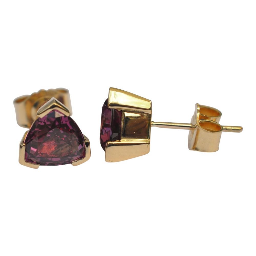 Rhodolite garnet and 18ct gold ear studs; the rich dark pinkish purple rhodolites are claw set, triangular in shape and weigh 3.46cts.  Measurements 0.80cm x 0.80cm x 0.60cm.  Weight 3.7gms.  The earrings are fixed with a post and butterfly which is