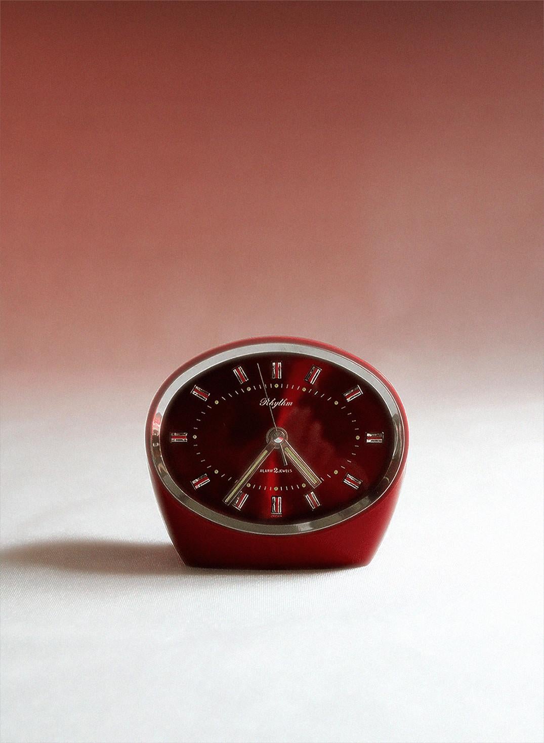 This rare and stylish vintage Rhythm Alarm Clock immediately falls within the Space Age style due to its shape. It was made in Japan in the 1960s by Rhythm, a Japanese company that has been making clocks since the 1950s. With the holographic face,