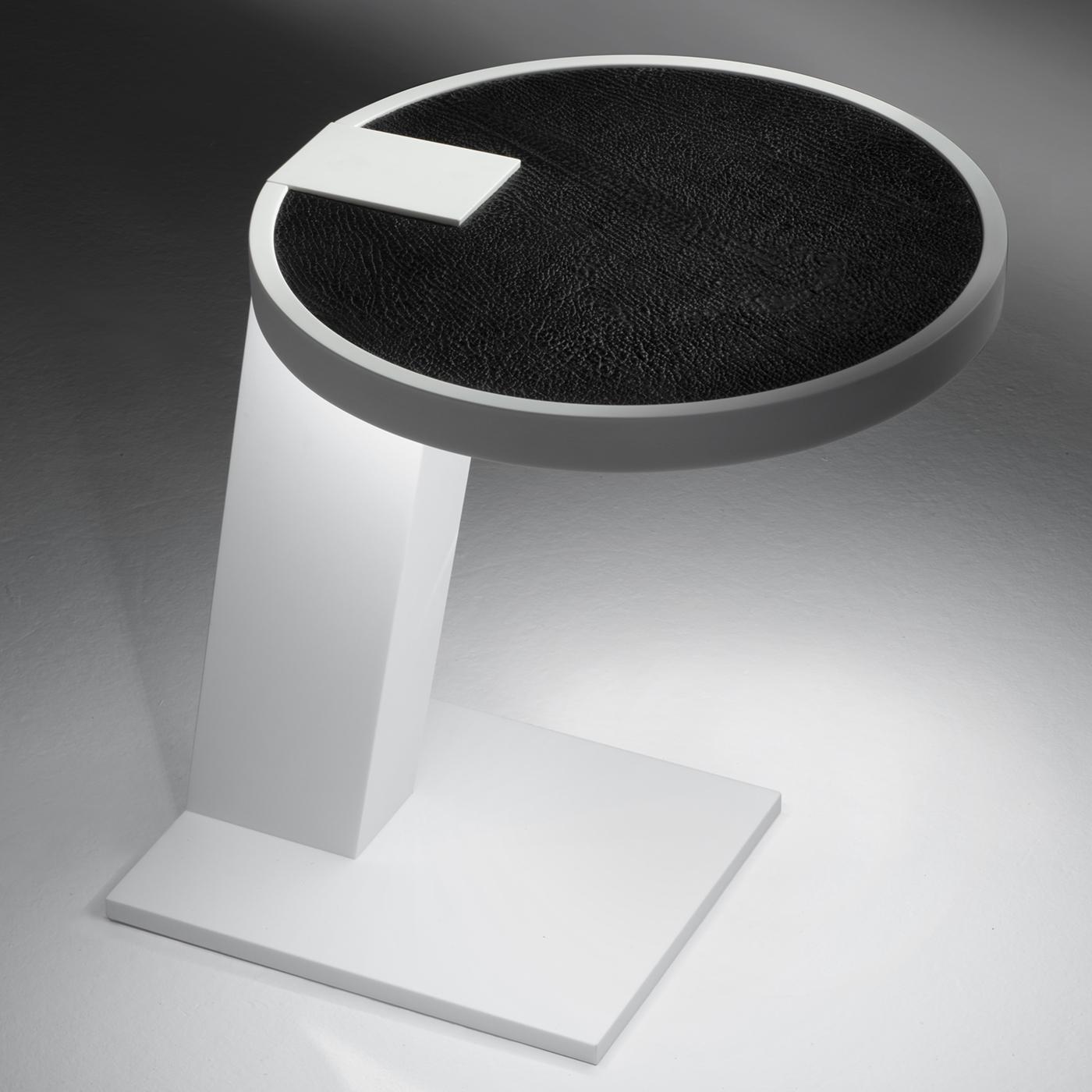 This sculptural work of art functions as a side table with pure geometric volumes and chromatic contrast. The smooth and silky Corian DuPont of the base serves as mounting for the sharkskin of the round top, which houses an infinity sensor that