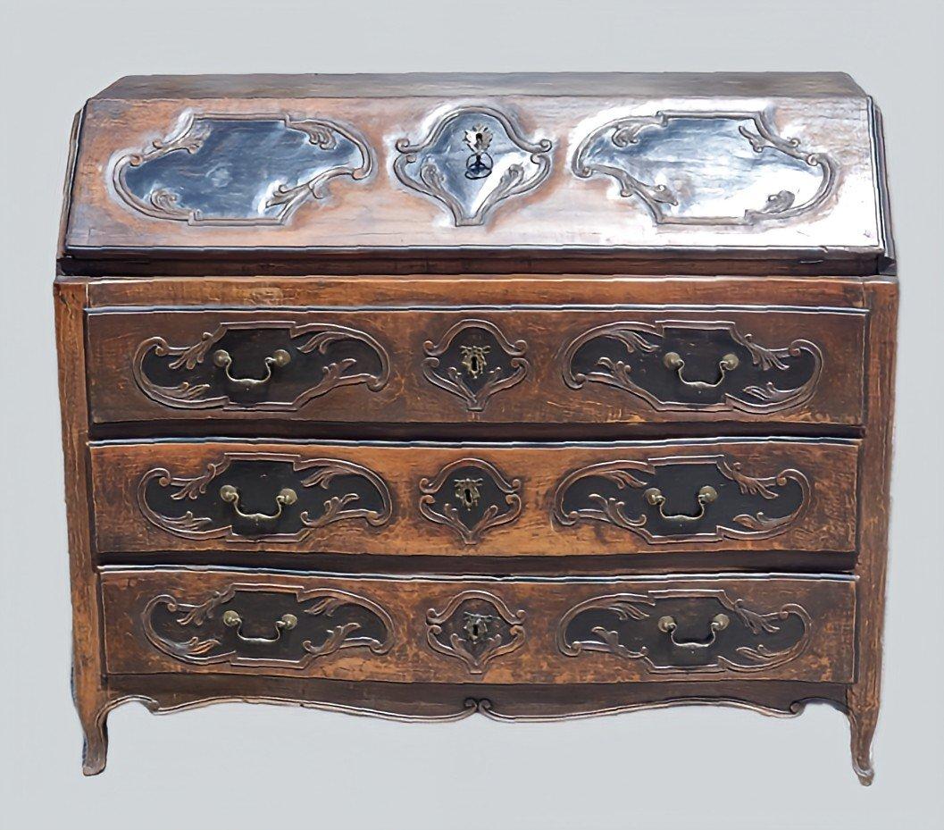 Elegante ribalta emiliana di manifattura parmigiana, databile alla metà del Settecento, pieno periodo Luigi XV. Mobile in legno massello scolpito, interamente intagliato a mano, con ricche decorazioni a motivi rocaille su fronte, fianchi e calatoia.